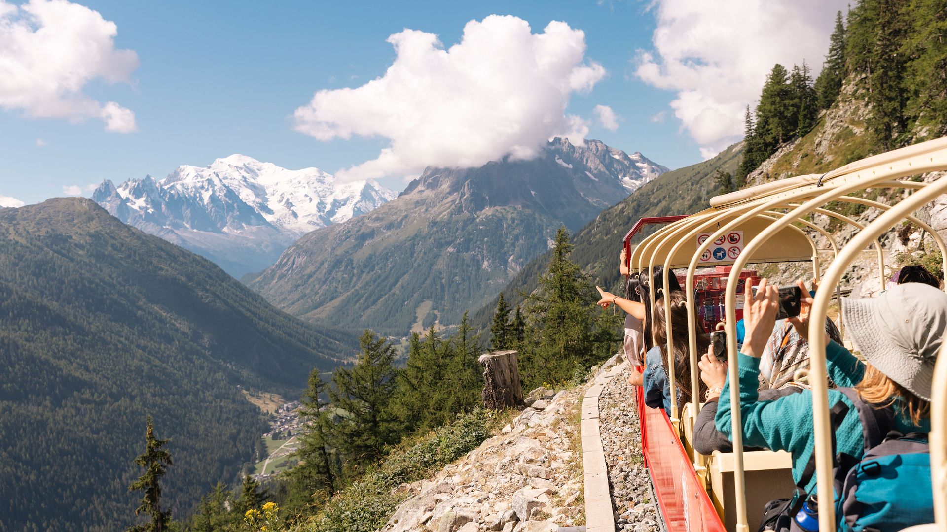 A red train moves through the mountains on a winding route.