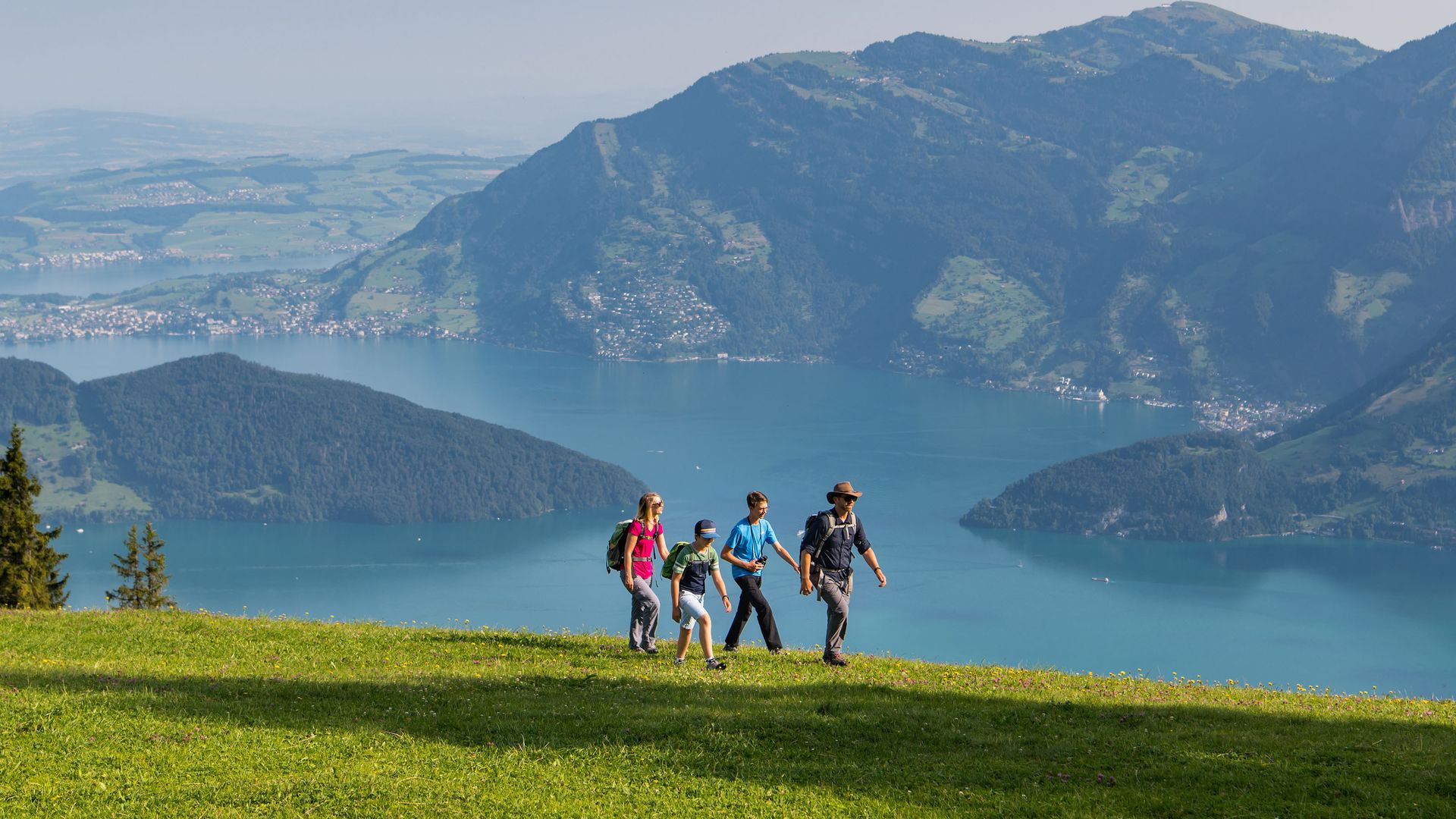 A hiking group on a green meadow on Klewenalp above Lake Lucerne.