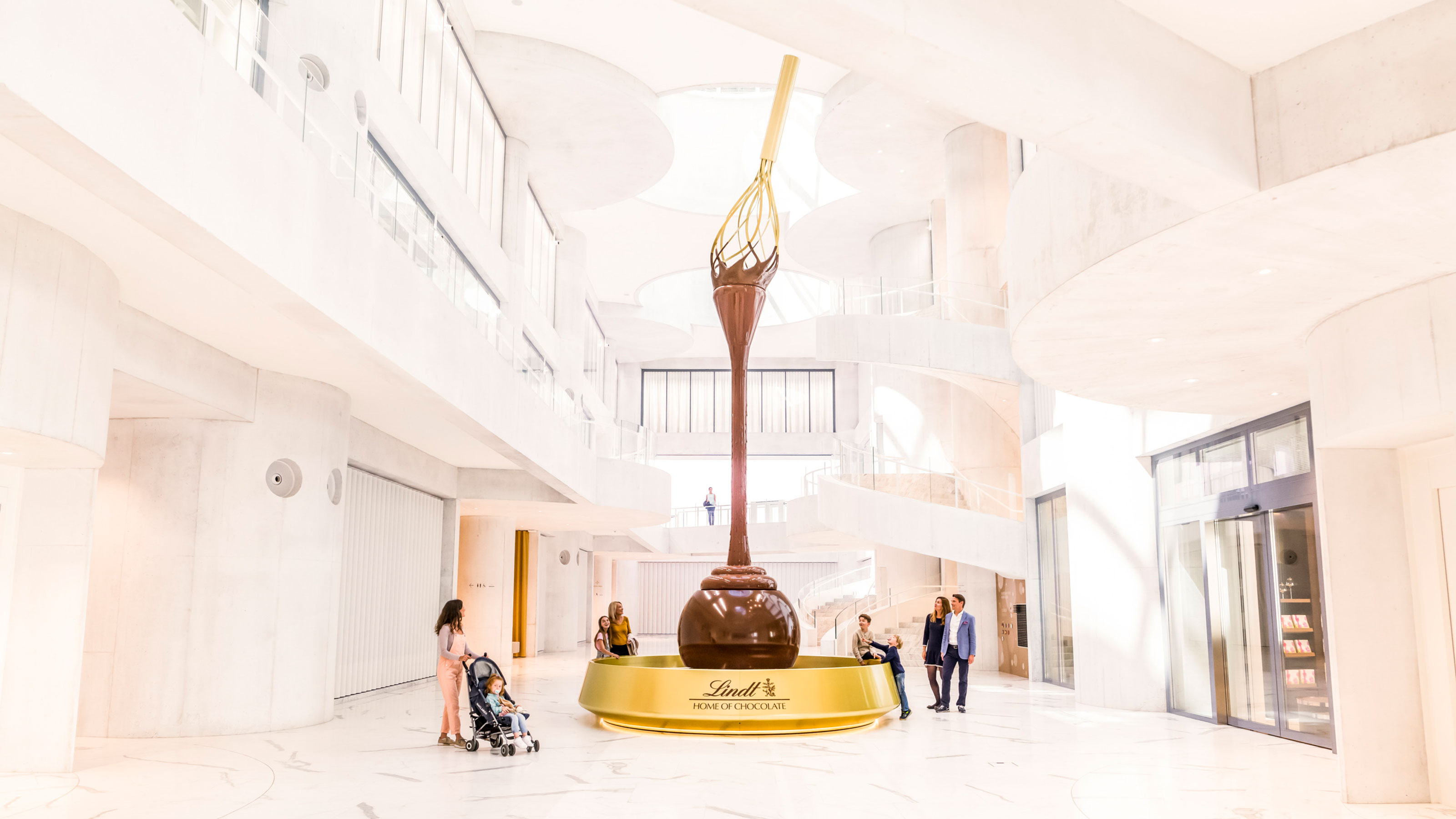  Grande sculpture représentant une cuillère en chocolat coulant dans l’intérieur lumineux et moderne du Lindt Home of Chocolate.
