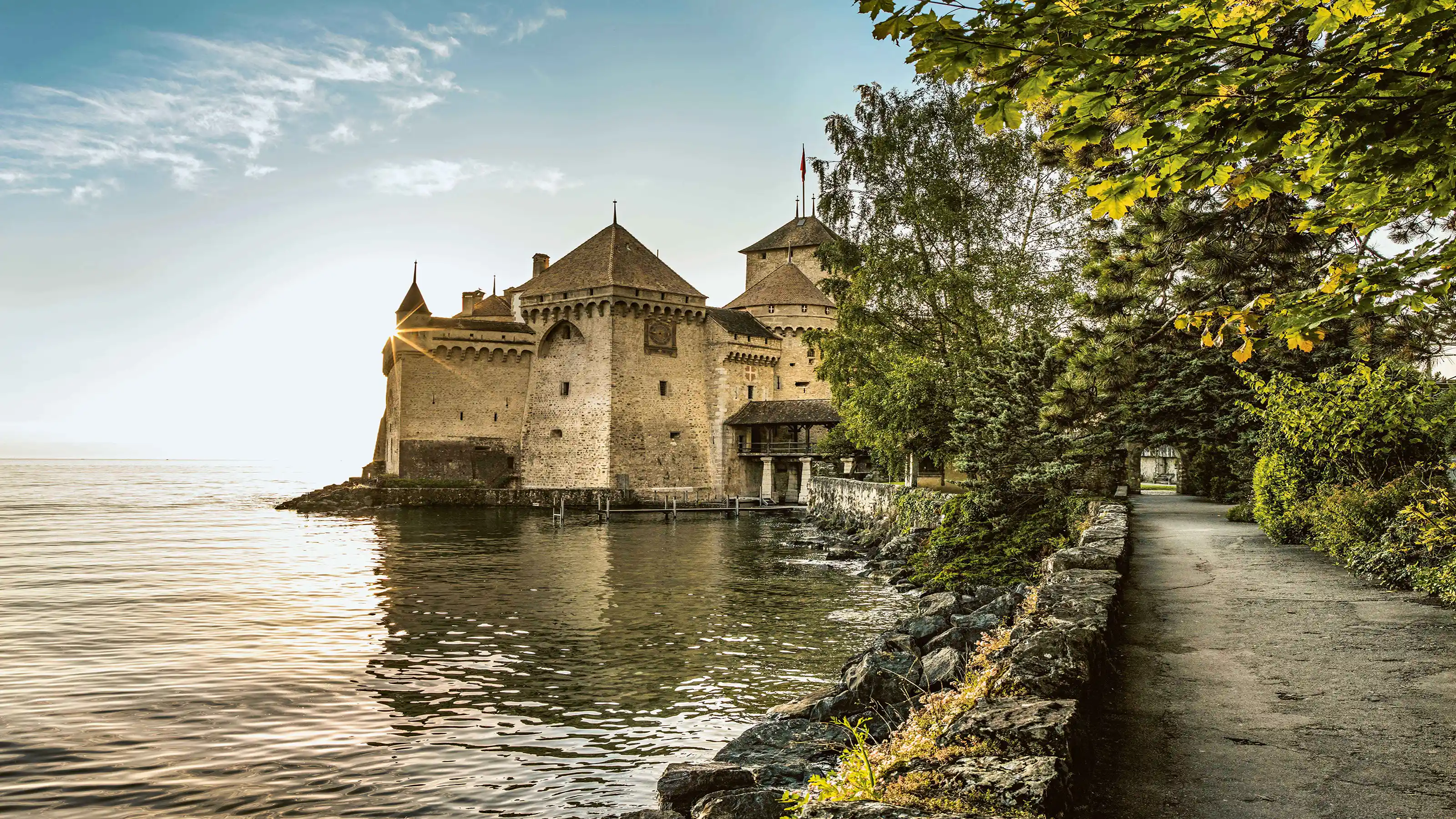 Un château se dresse de manière pittoresque au bord d'un lac, entouré d'un paysage idyllique.