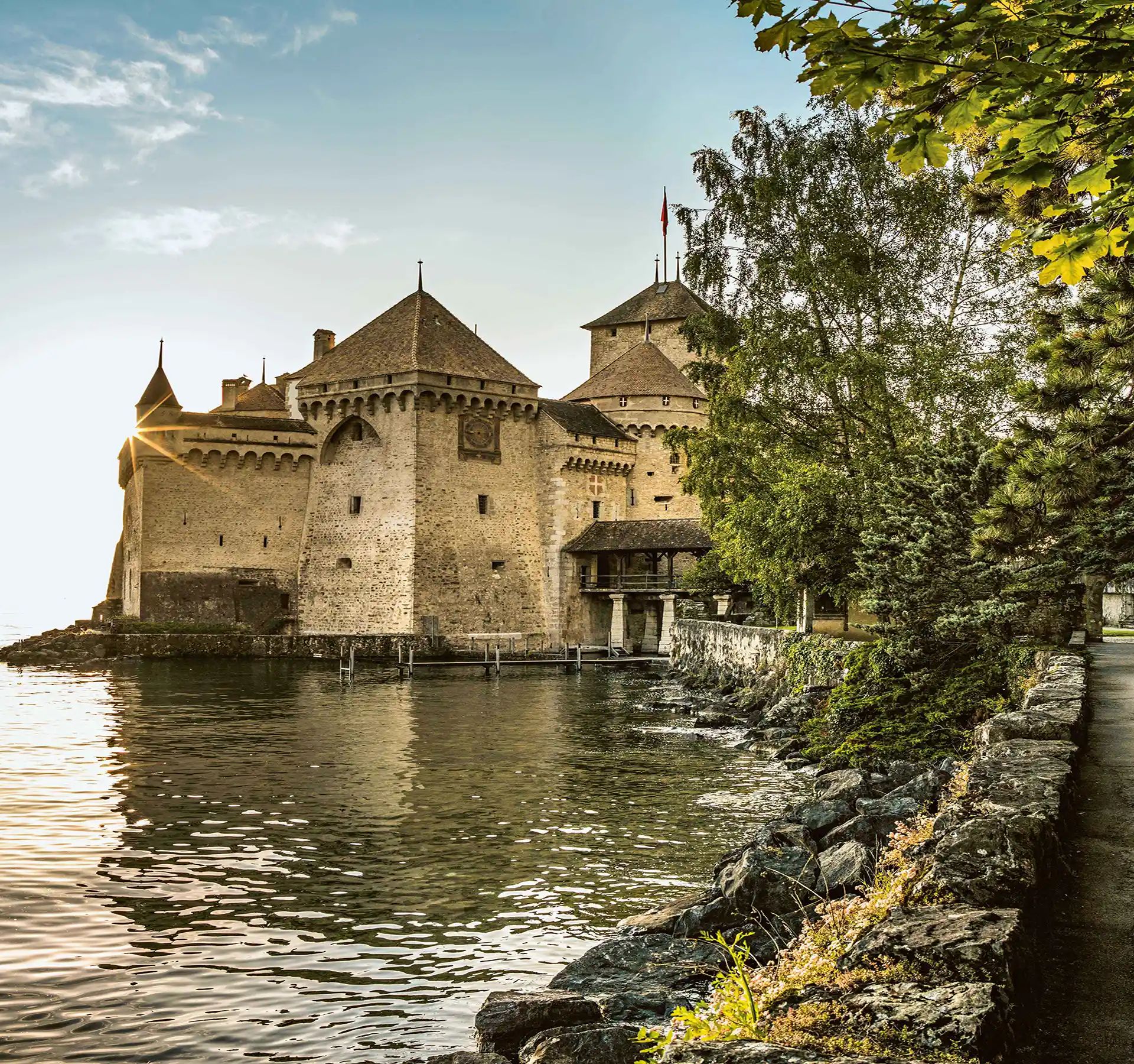 Un château se dresse de manière pittoresque au bord d'un lac, entouré d'un paysage idyllique.
