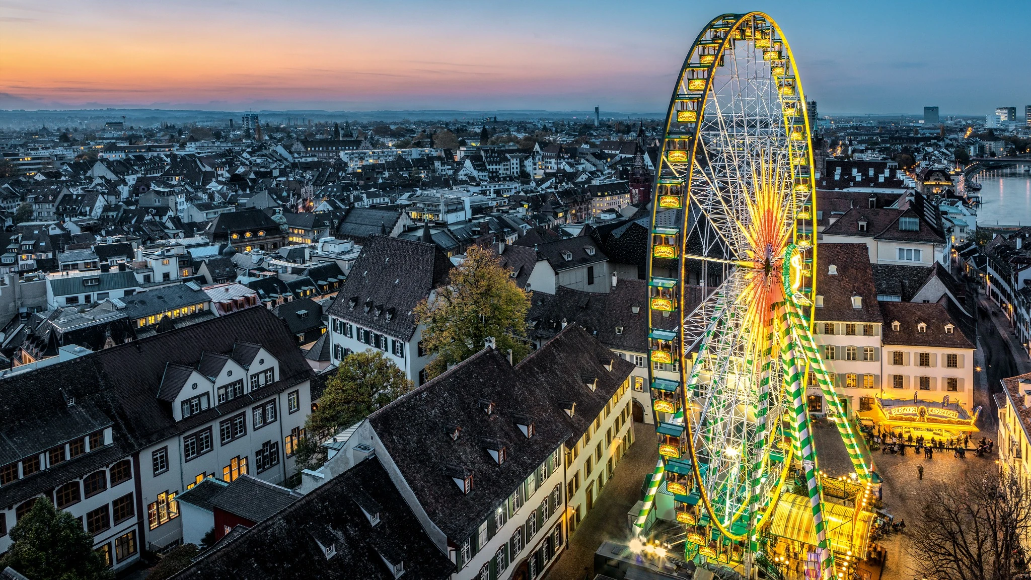 Grande roue illuminée à la Foire d’automne de Bâle au crépuscule. 