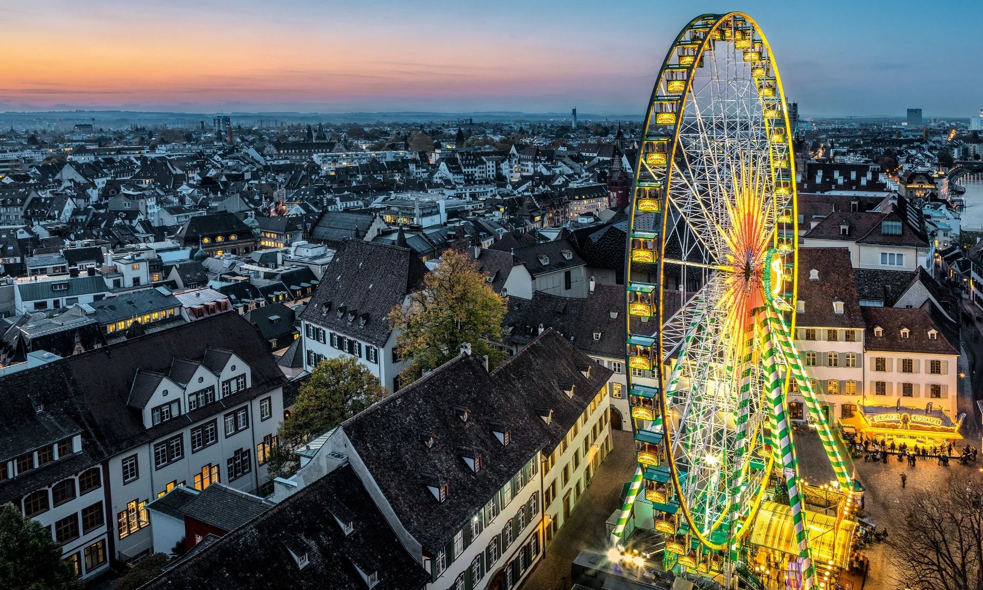 Grande roue illuminée à la Foire d’automne de Bâle au crépuscule.