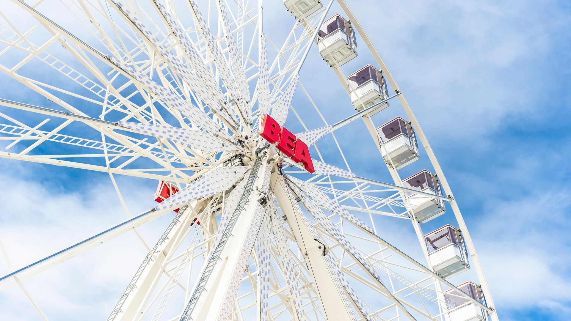 Ferris wheel at the BEA fair in Bern with colorful cabins, visitors, and a sunny sky in the background.