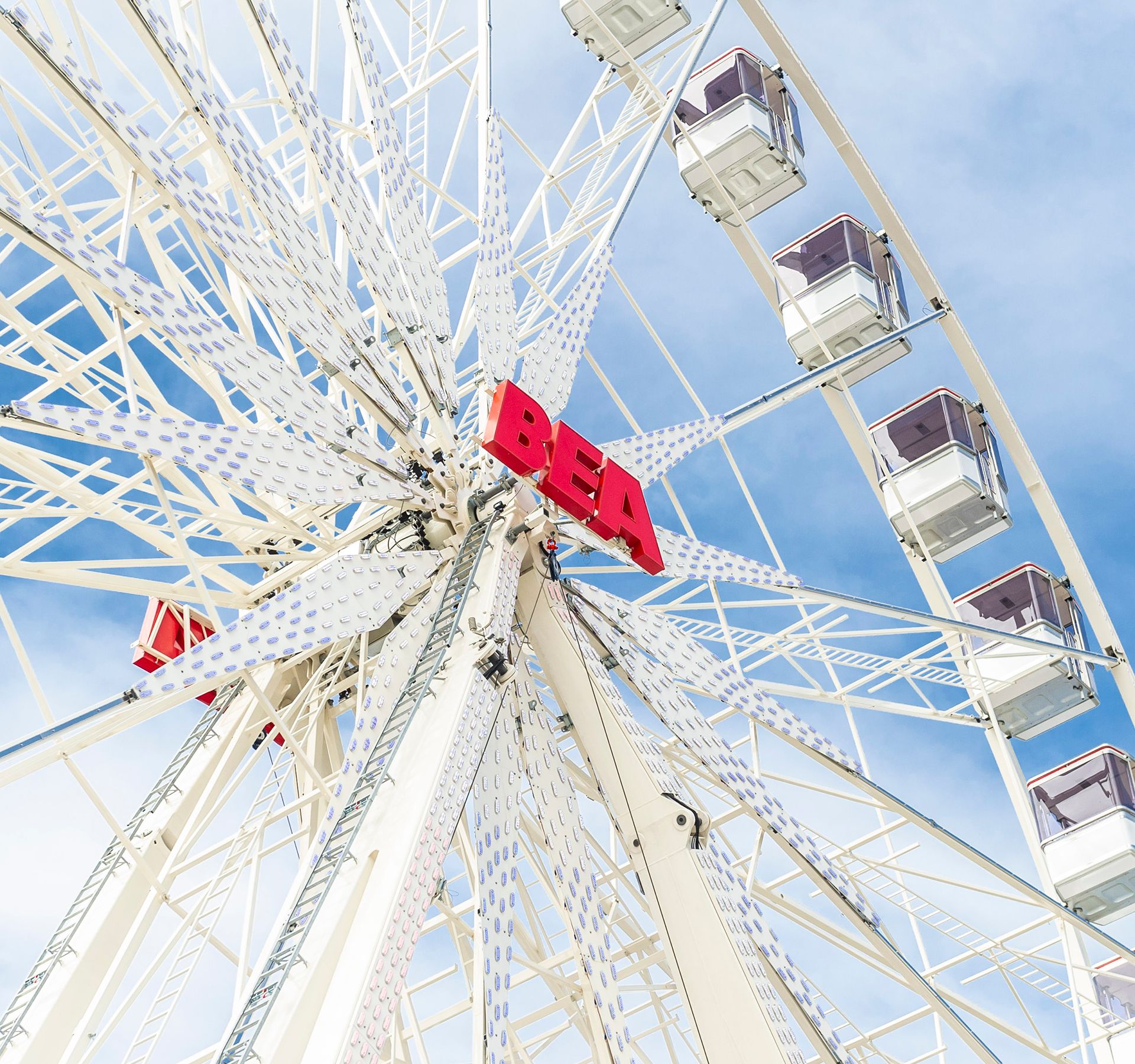 Riesenrad auf der BEA-Messe in Bern mit bunten Gondeln, Besuchern und sonnigem Himmel im Hintergrund.