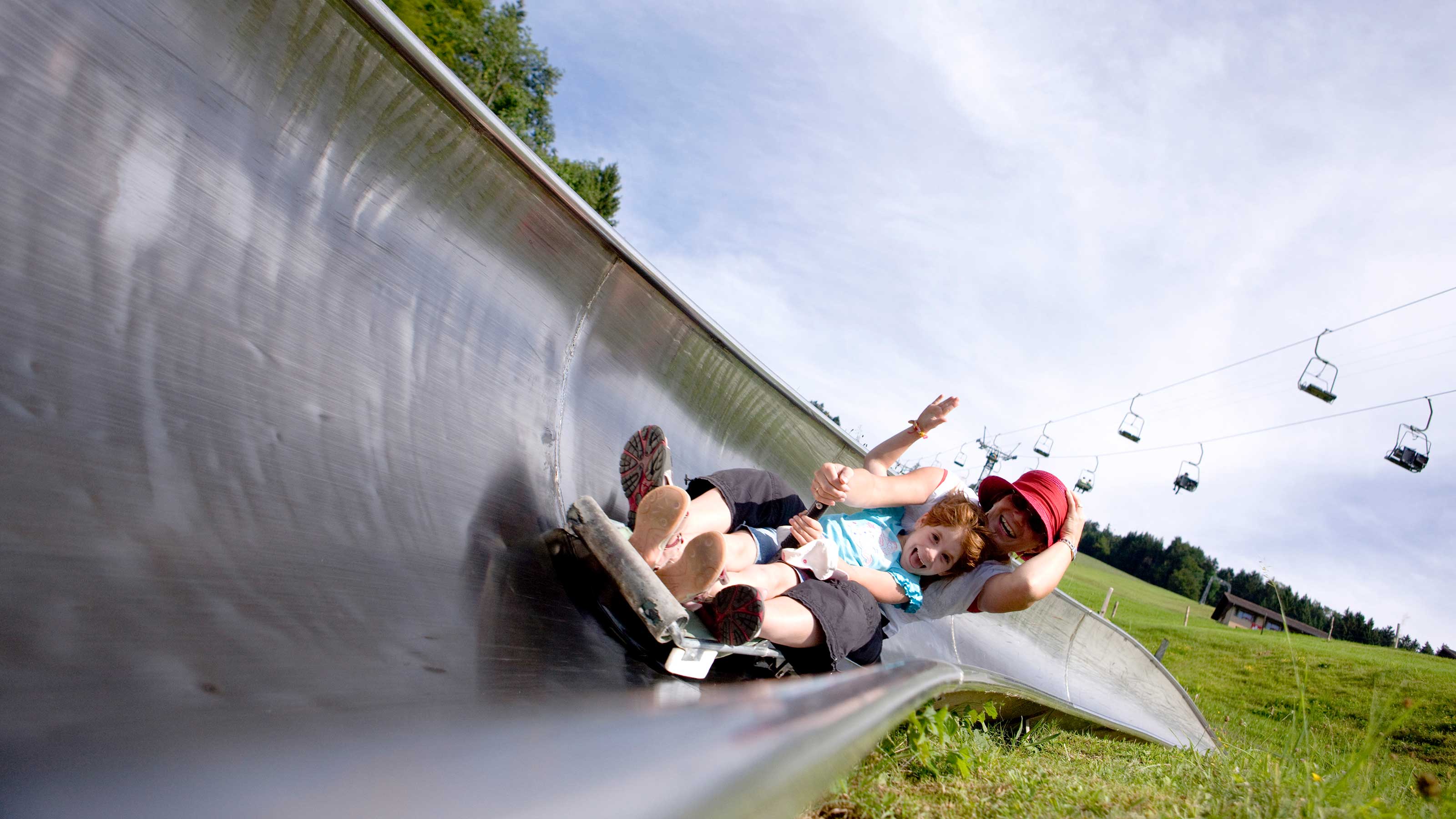 Une fille et une femme ensemble à pleine vitesse sur une piste de luge.