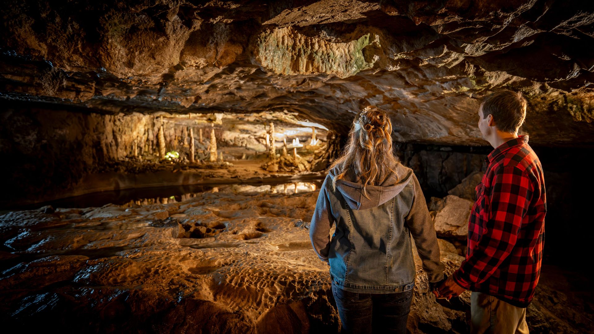 Due persone in piedi in una grotta e osservano con attenzione il vasto panorama.