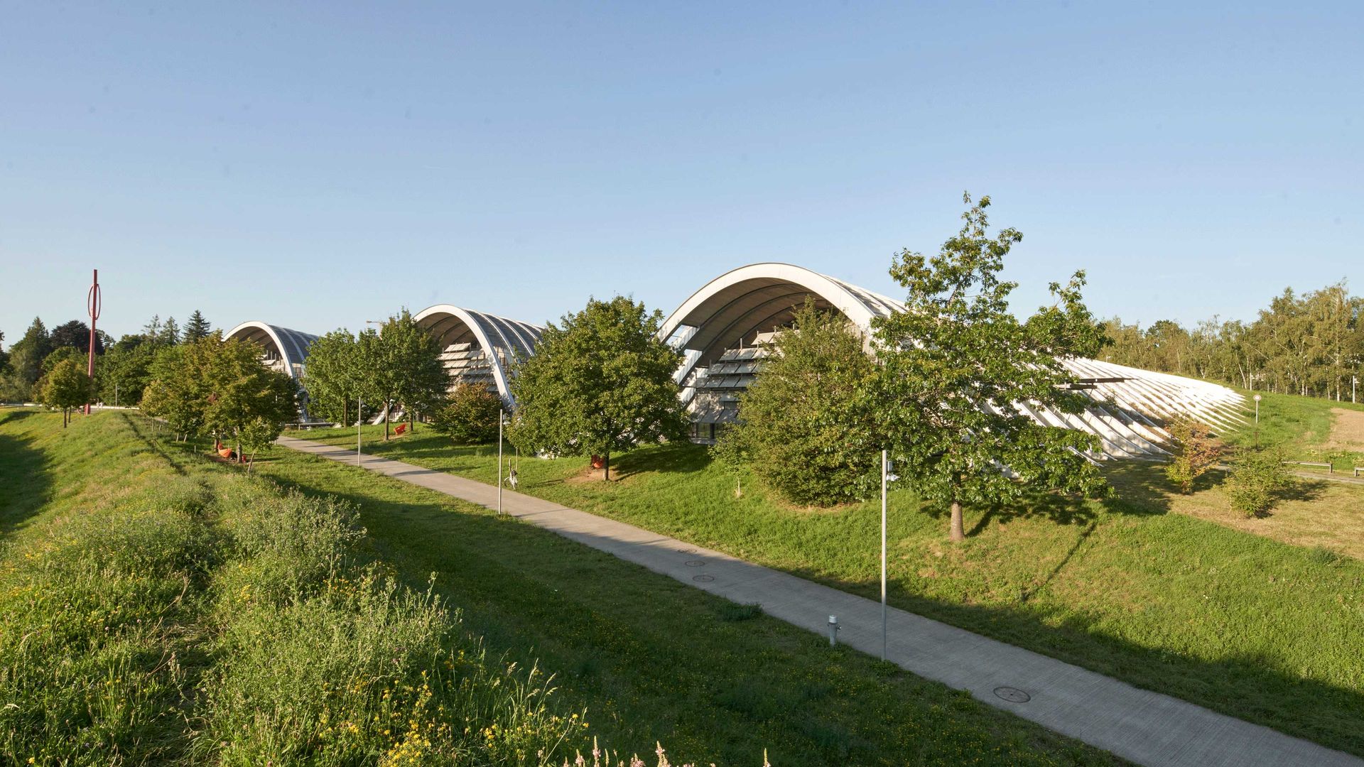 Modern building with curved roofs in a green, sunny landscape