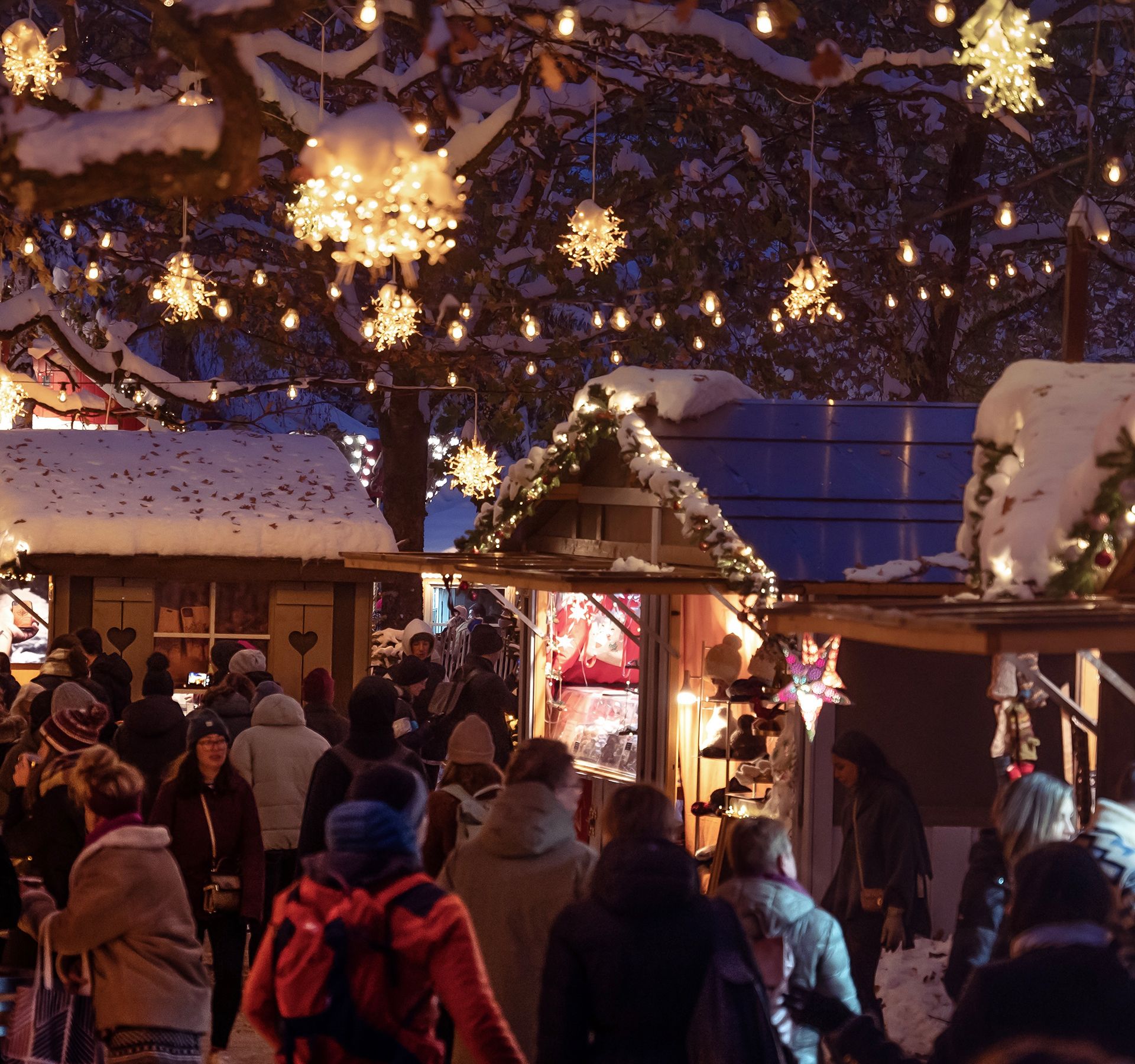 La sera le persone visitano un mercatino di Natale illuminato.
