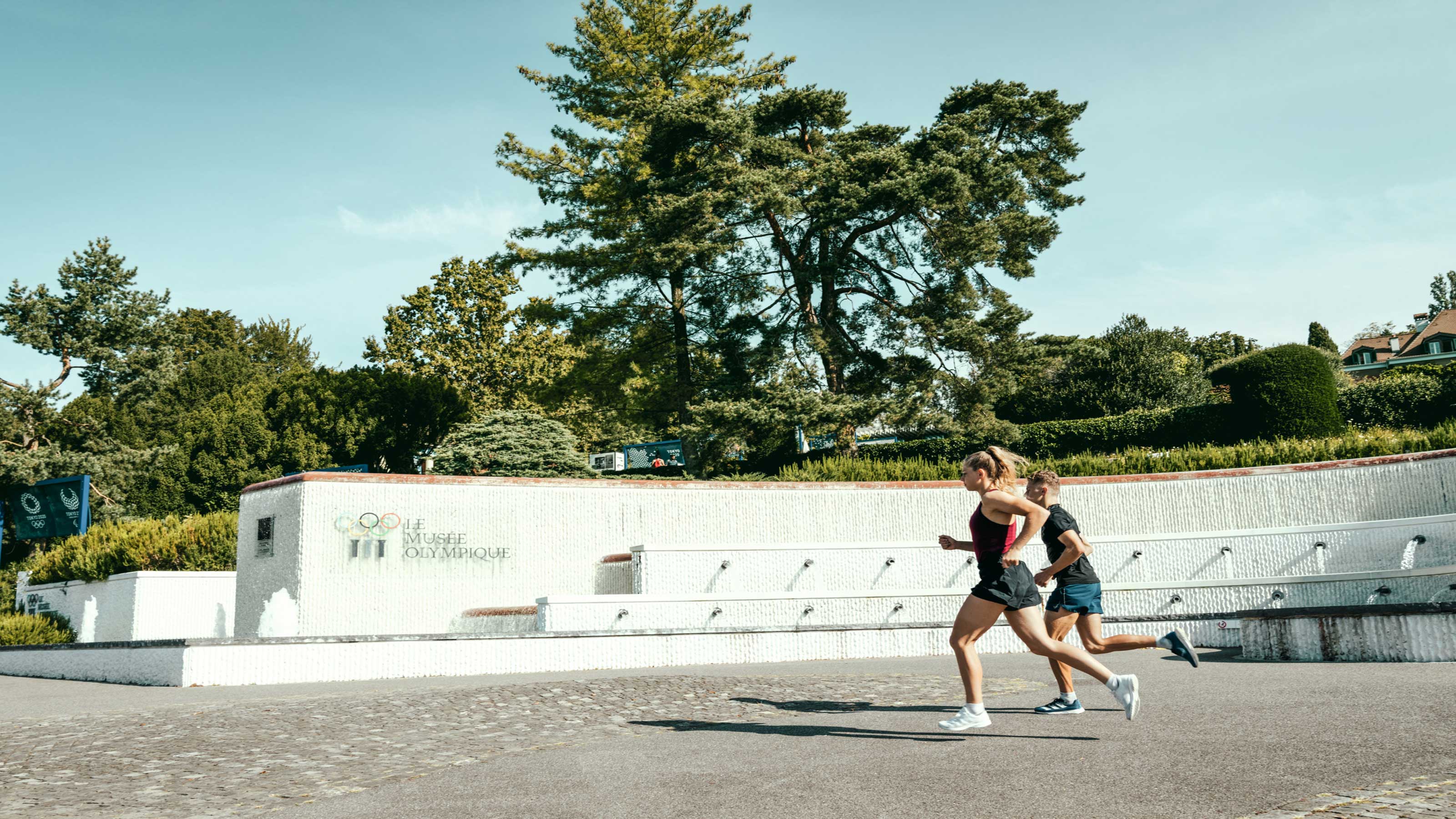Two joggers running through an old town street in daylight.