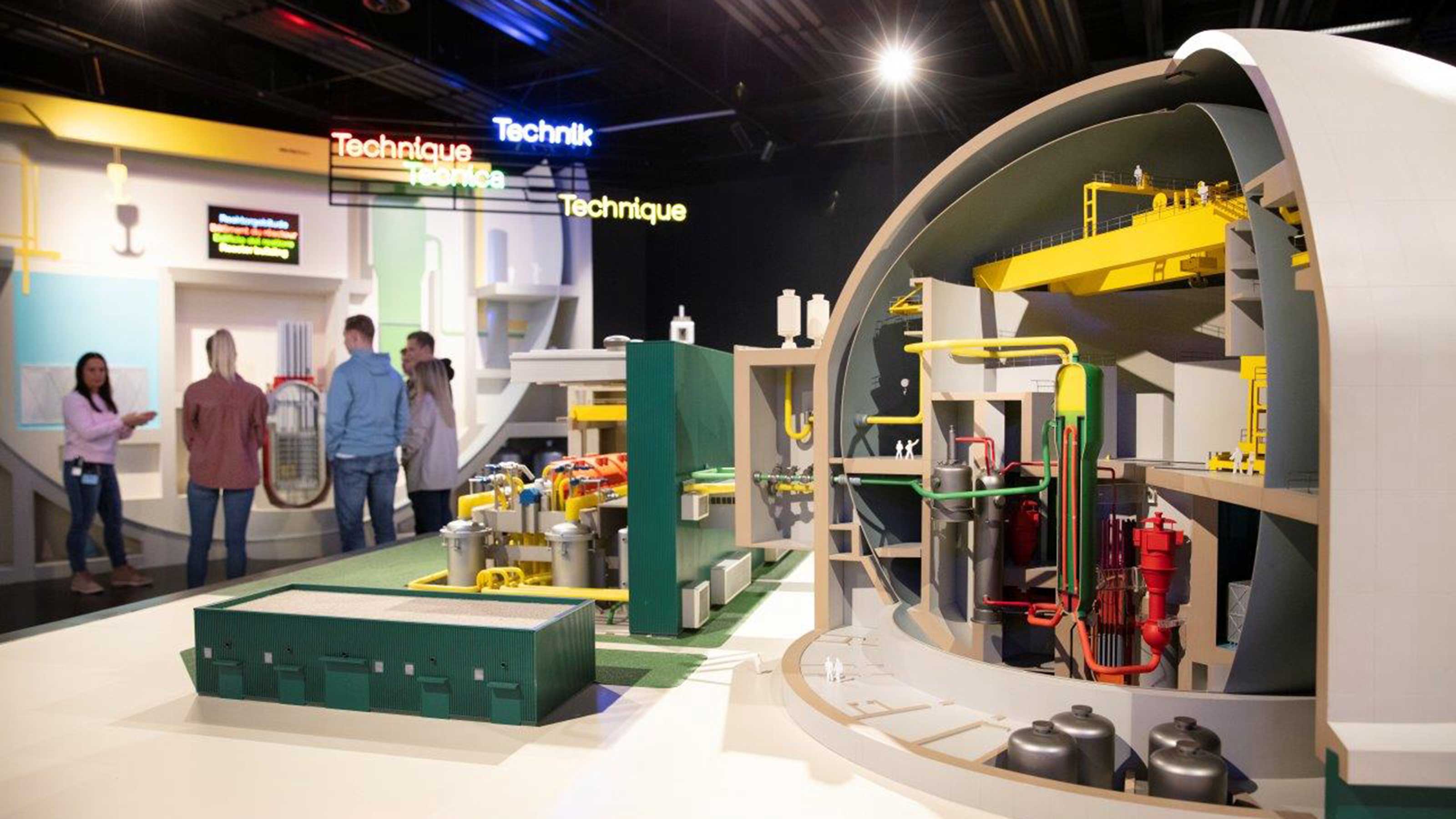 Un modello mostra l'interno della centrale nucleare. Sullo sfondo c'è un gruppo di persone che segue con attenzione la guida.