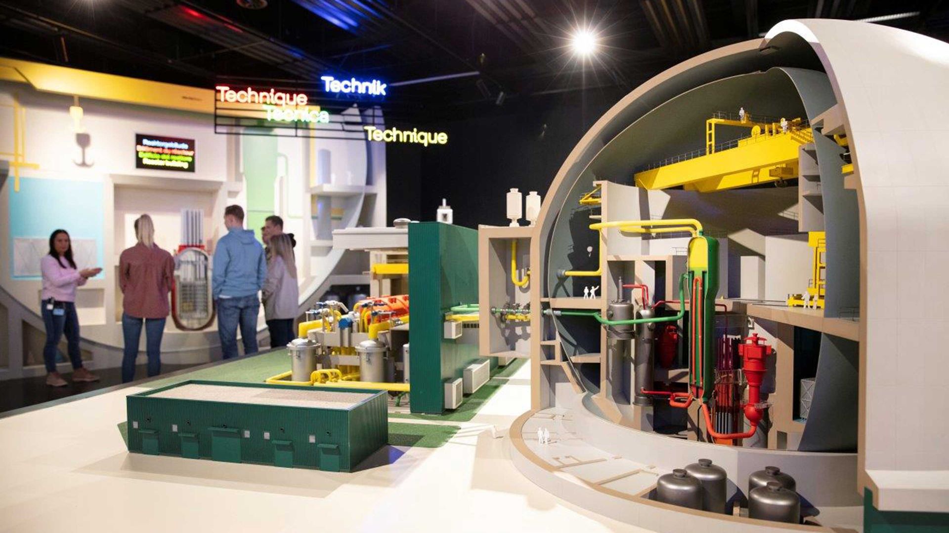 Une maquette montre l'intérieur de la centrale nucléaire. En arrière-plan se trouve un groupe de personnes qui suivent attentivement le guide.