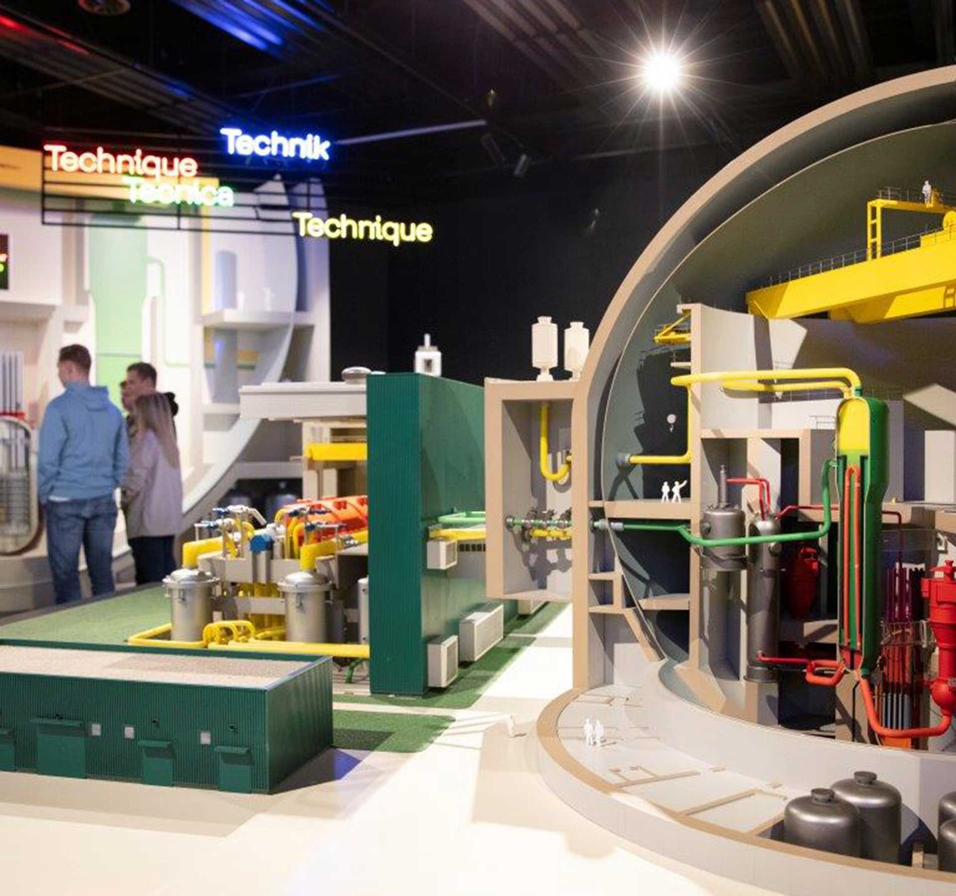 Une maquette montre l'intérieur de la centrale nucléaire. En arrière-plan se trouve un groupe de personnes qui suivent attentivement le guide.