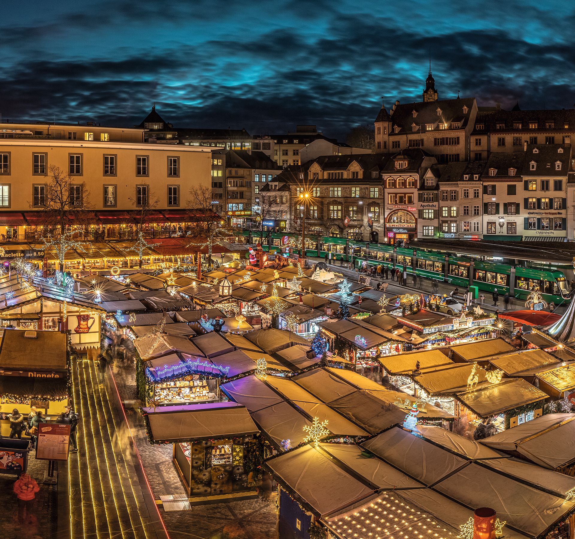 A festive Christmas market at night with colourfully decorated wooden stalls.