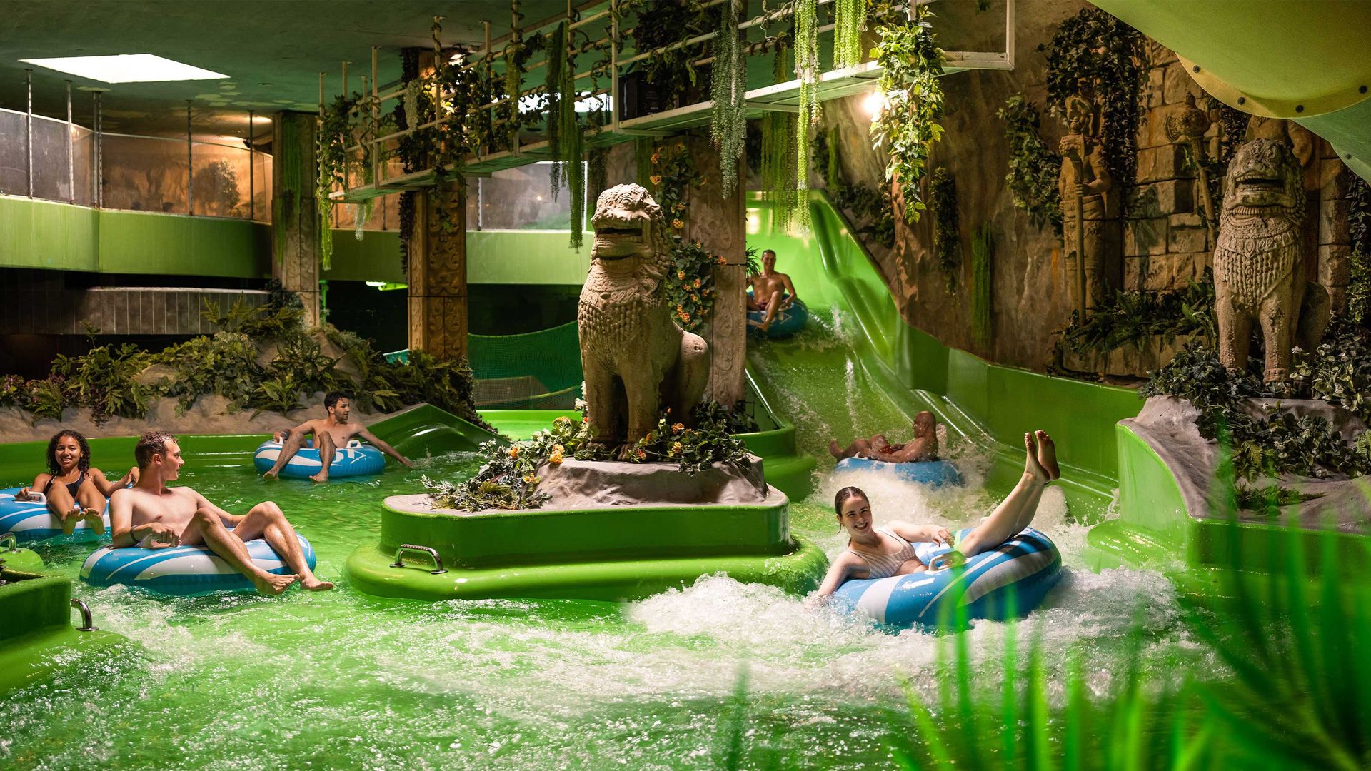 Des enfants s'amusent sur des toboggans en caoutchouc dans un parc aquatique intérieur.