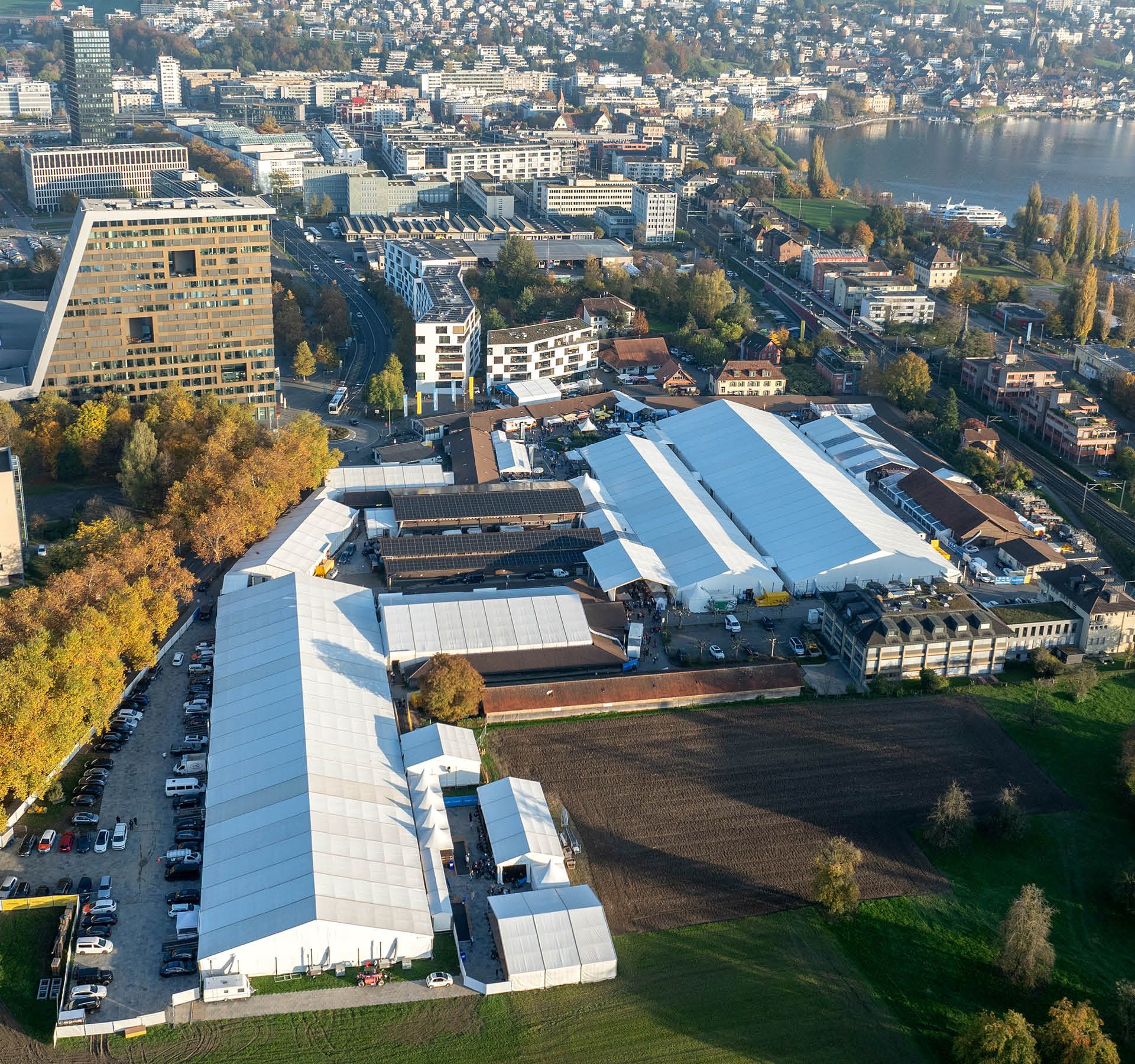 Zug Fair 2026: with exhibition tents, surrounded by city buildings and Lake Zug in the background.