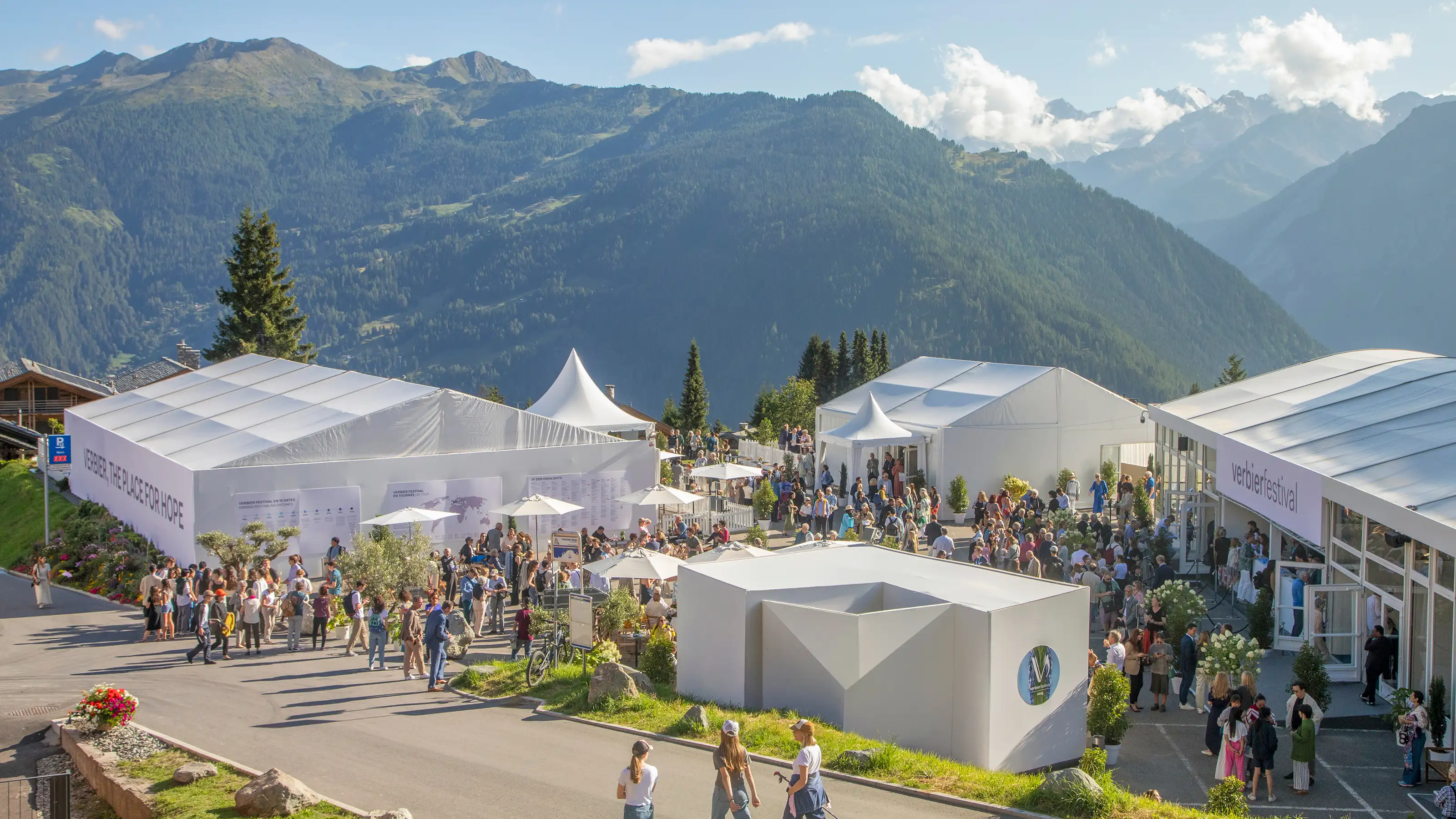 Menschenmenge vor und in einem grossen weissen Zelt mit dem Schriftzug verbierfestival in einer Berglandschaft.