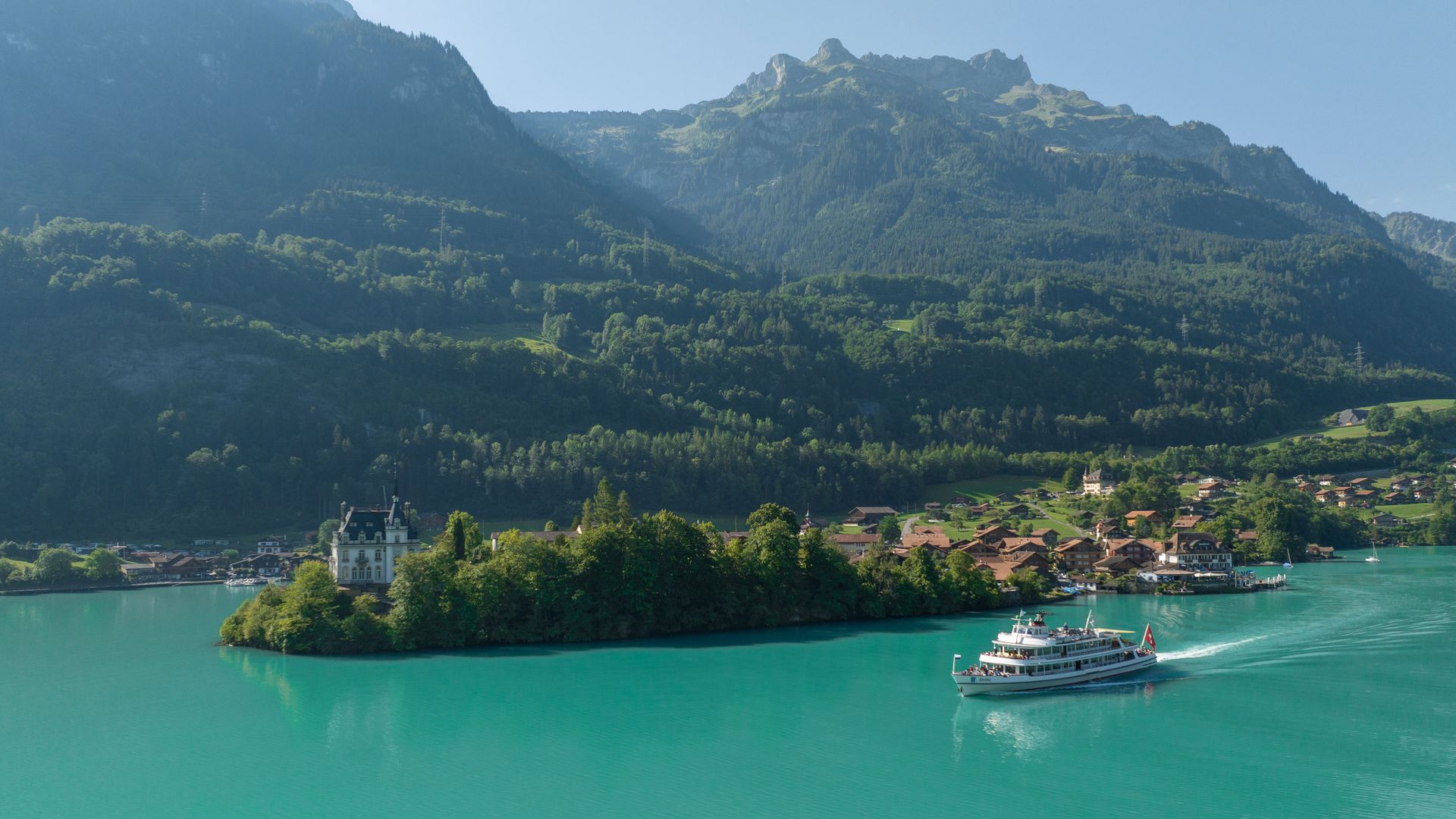 Ein Schiff fährt auf dem Thunersee. Im Hintergrund sieht man Eiger, Mönch und Jungfrau.