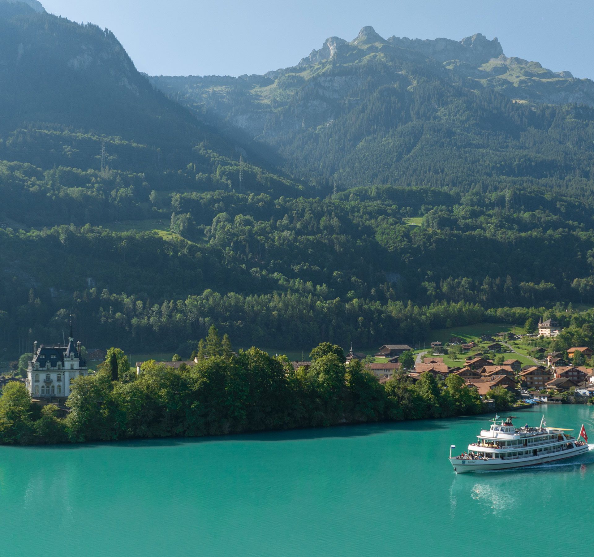 Ein Schiff fährt auf dem Thunersee. Im Hintergrund sieht man Eiger, Mönch und Jungfrau.