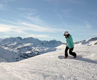 Eine Person fährt mit einem Snowboard auf einer verschneiten Piste.