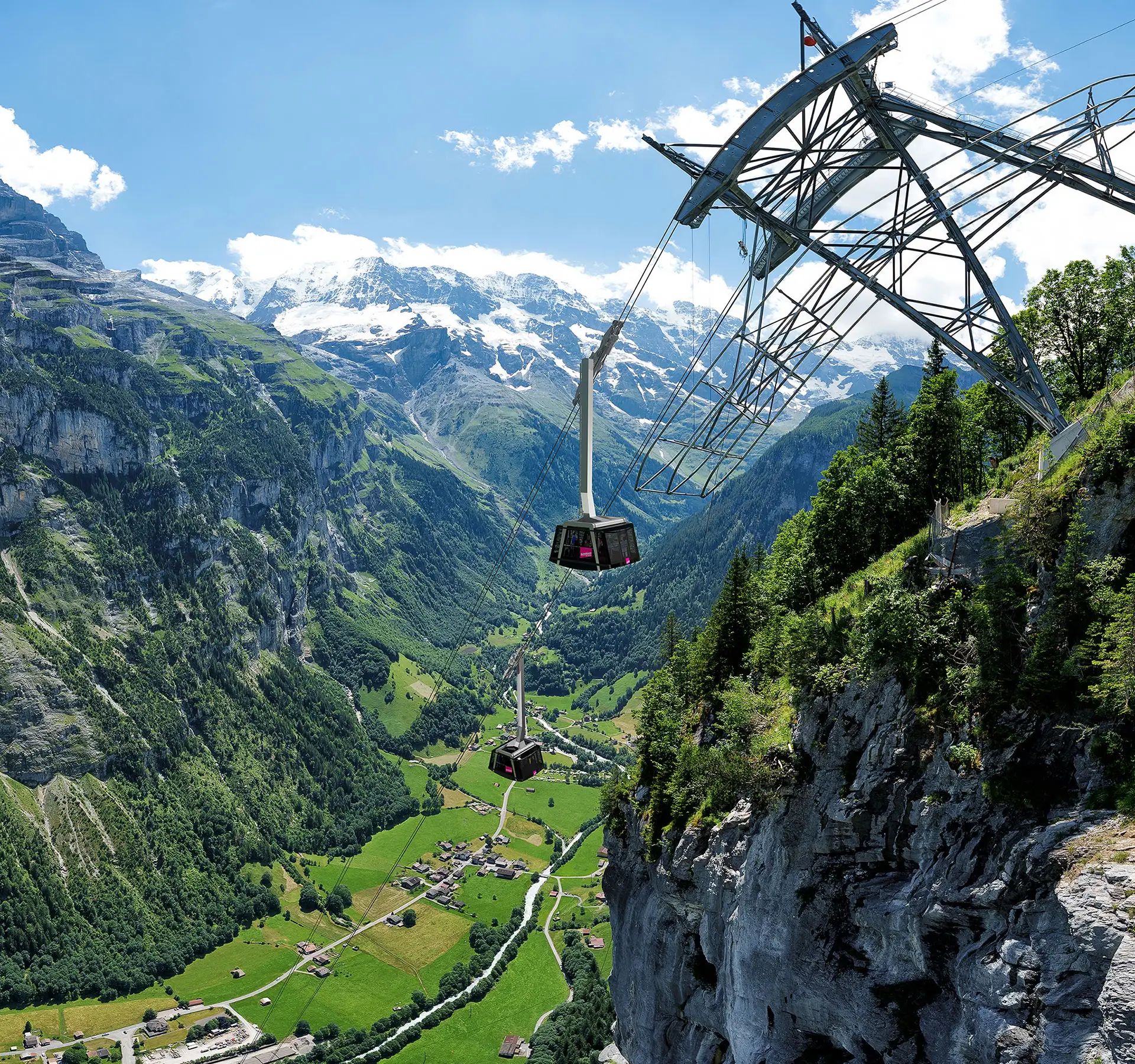 Schilthorn Seilbahn mit Gondeln an steiler Felswand über grünem Tal mit Berggipfeln im Hintergrund.