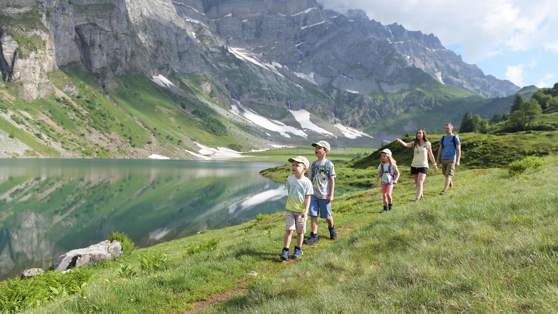 Une famille se promène le long du lac Oberblegi dans une prairie de montagne.