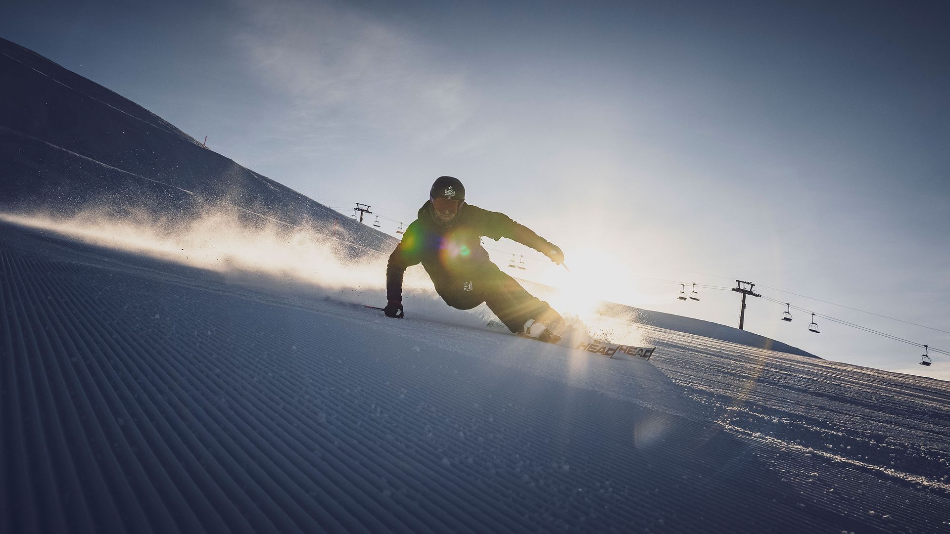 Ein Skifahrer gleitet bei morgendlicher Stimmung über eine perfekt präparierte Piste.