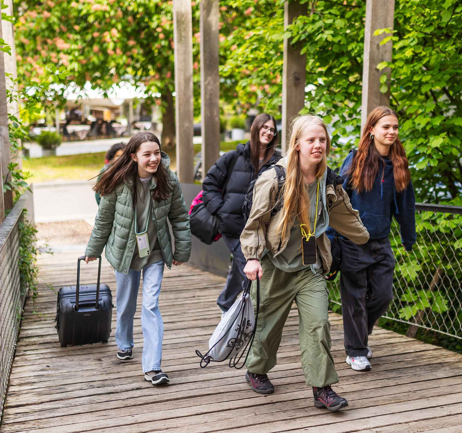 Quattro ragazze corrono su una rampa di legno fino all'ingresso dell'ostello della gioventù.