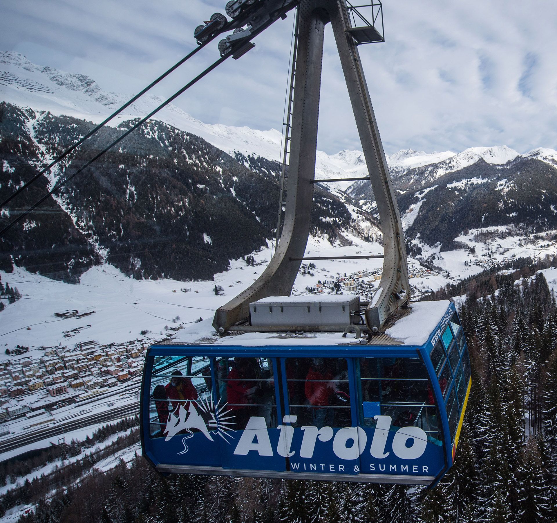 Eine Seilbahn gleitet durch schneebedeckte Bäume in einer ruhigen Berglandschaft.