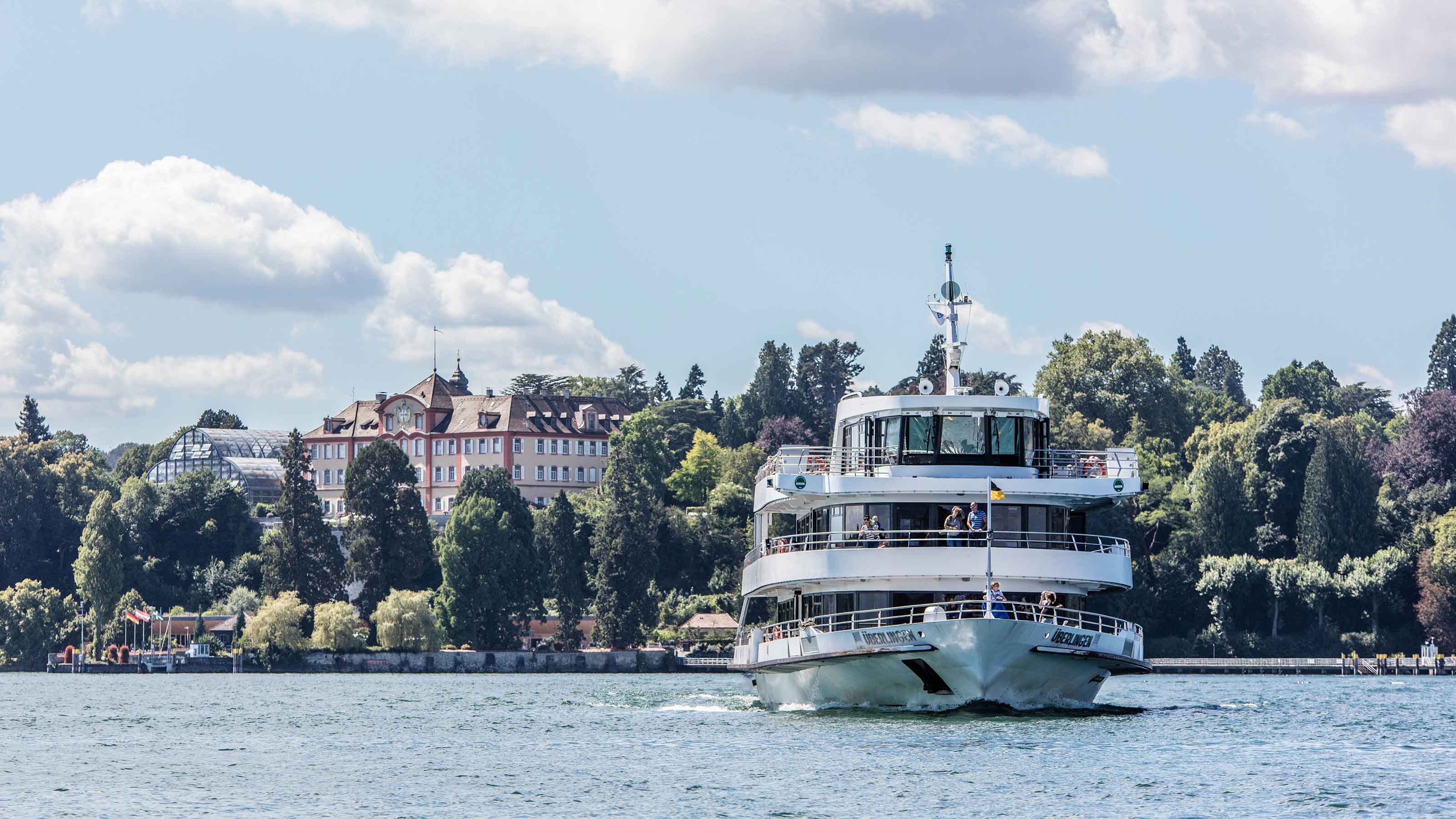 Un battello con passeggeri si allontana dalla riva.