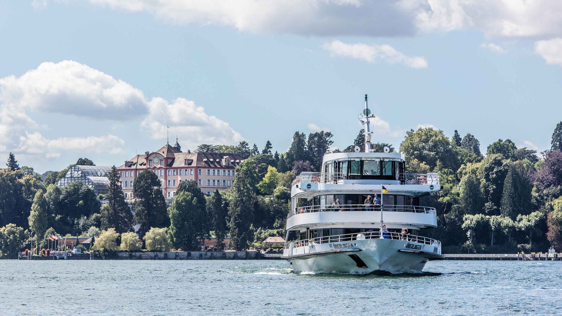 Un battello con passeggeri si allontana dalla riva.