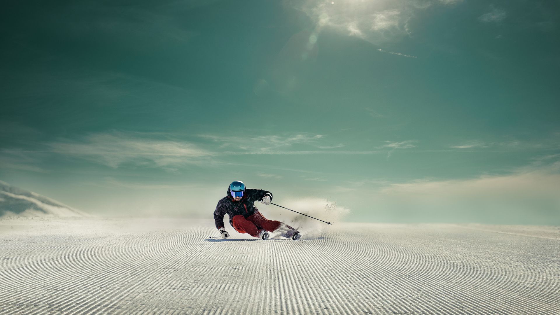Skifahrer in roter Hose und blauem Helm fährt auf frisch präparierter Piste im Skigebiet Engelberg Titlis bei blauem Himmel.