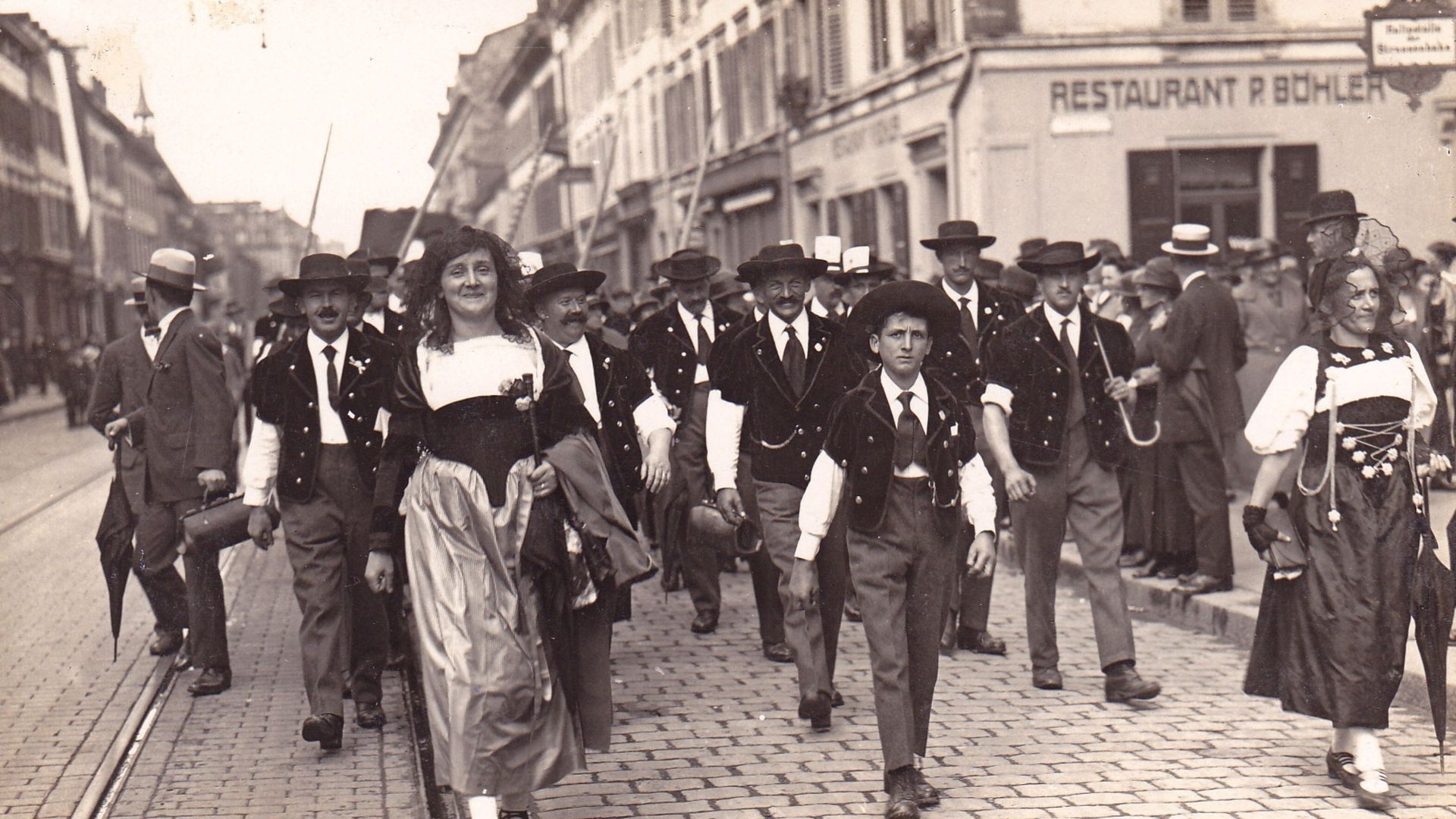 Historisches Schwarzweissfoto einer Jodlergruppe in Tracht beim Auftritt auf einem Festplatz.