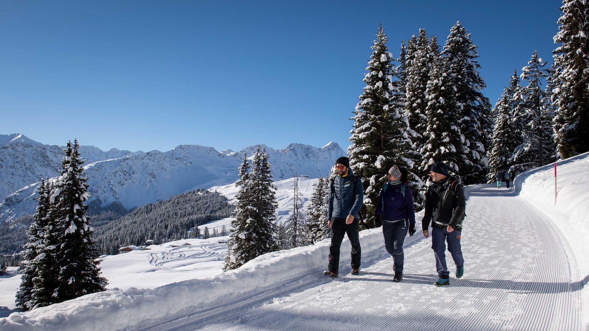A group of winter hikers walks along a perfectly groomed winter hiking trail. 