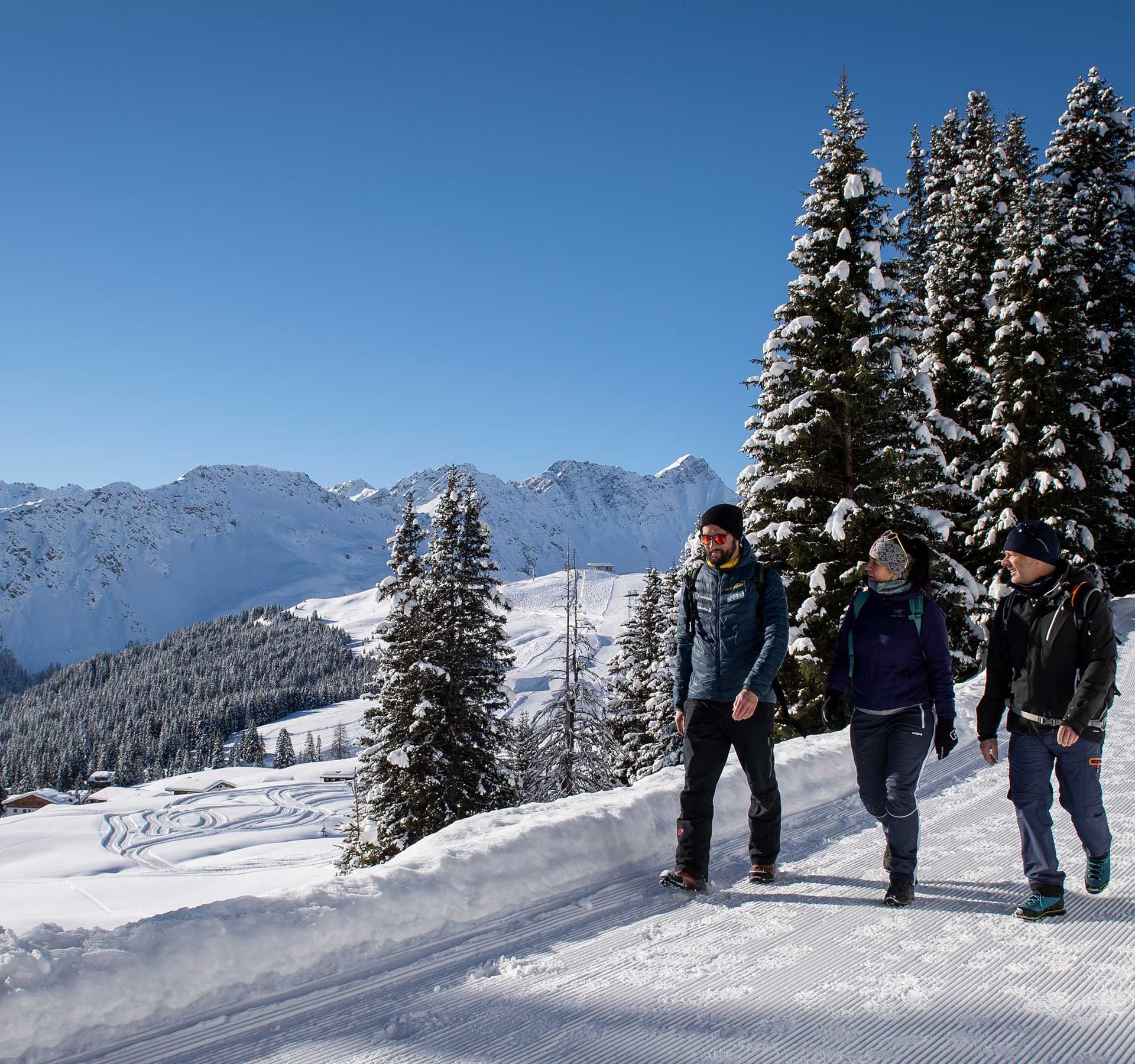 A group of winter hikers walks along a perfectly groomed winter hiking trail.