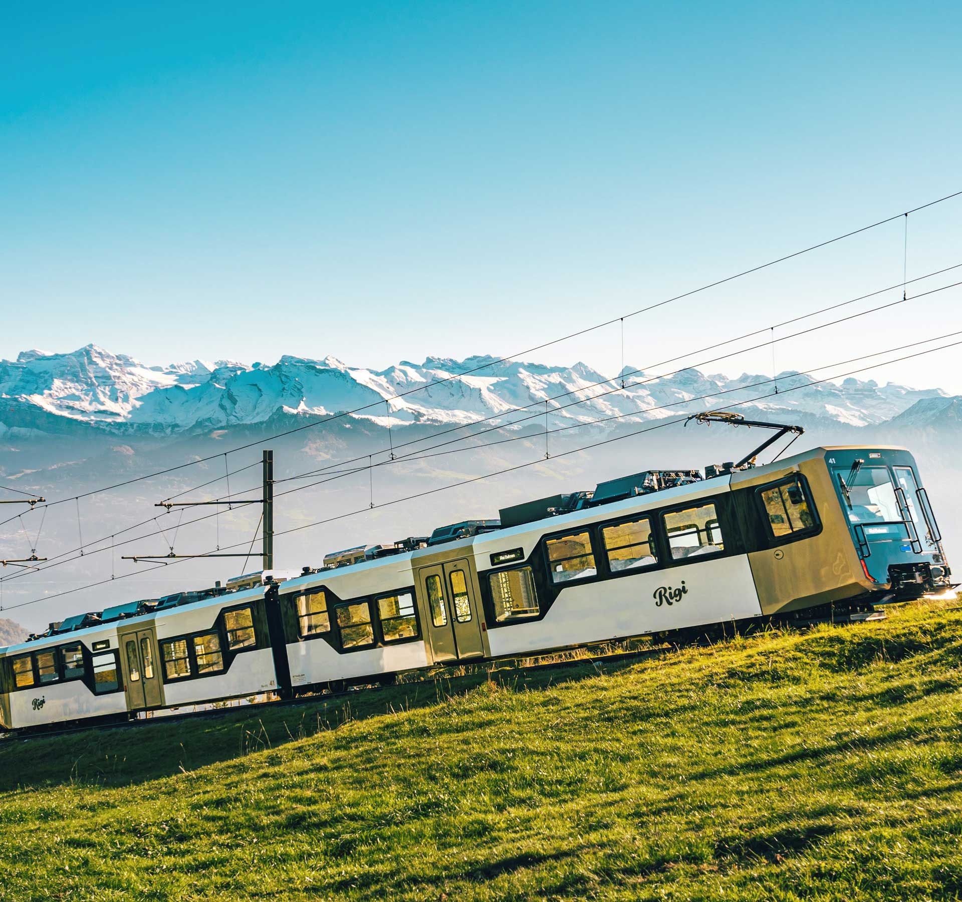 Una ferrovia bianca del Rigi in viaggio verso la vetta. Sullo sfondo si vede il magnifico panorama montano.