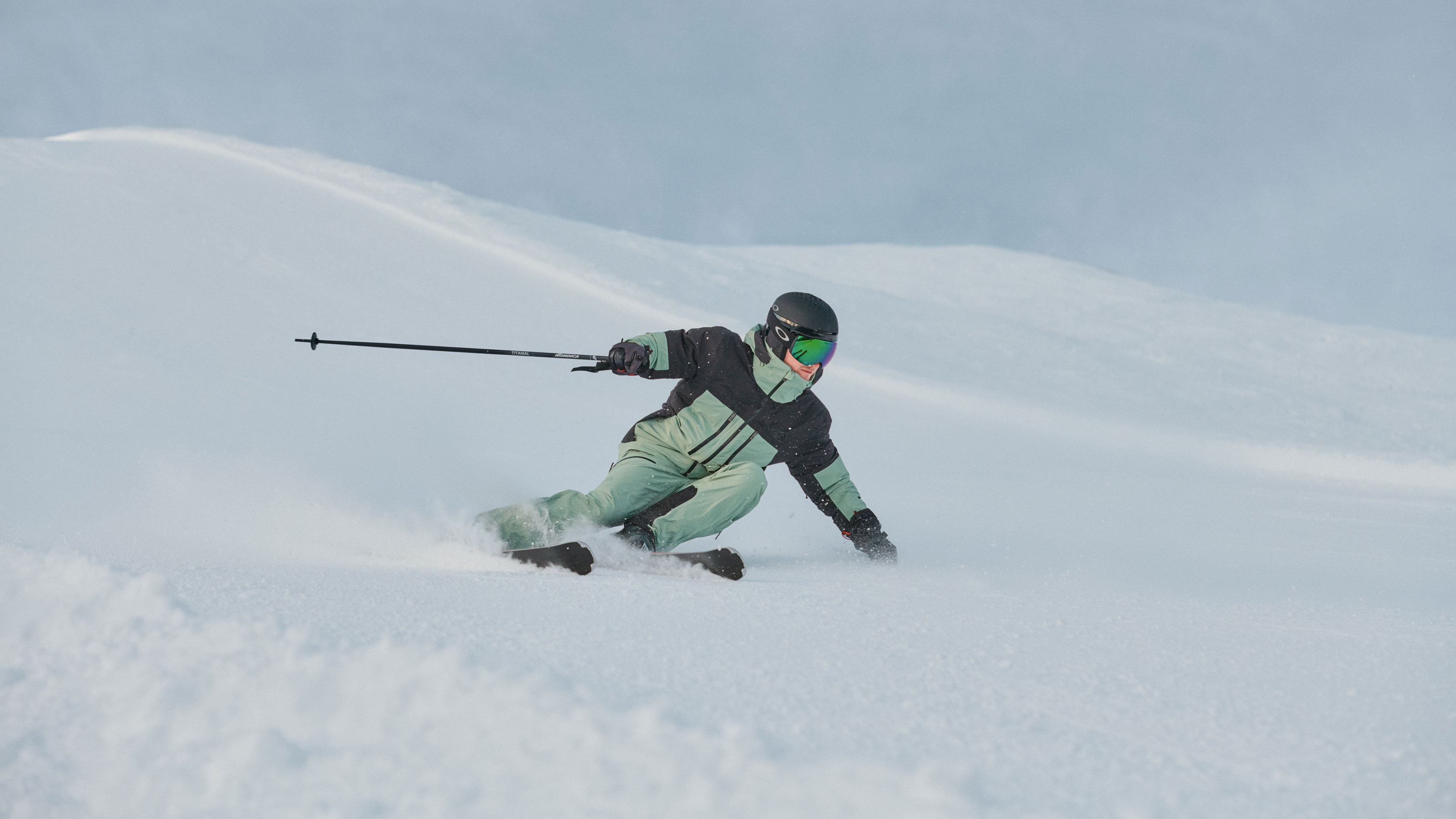 Eine Person fährt gekonnt auf Skiern einen verschneiten Hang hinunter und zeigt ihre Technik vor einer winterlichen Kulisse.