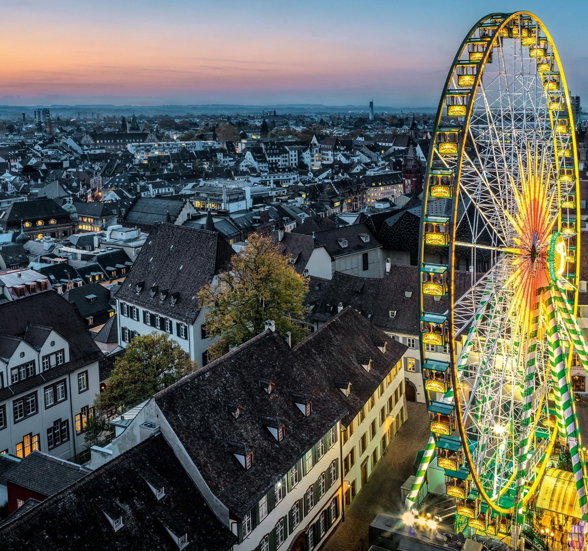Beleuchtetes Riesenrad an der Basler Herbstmesse bei Dämmerung.