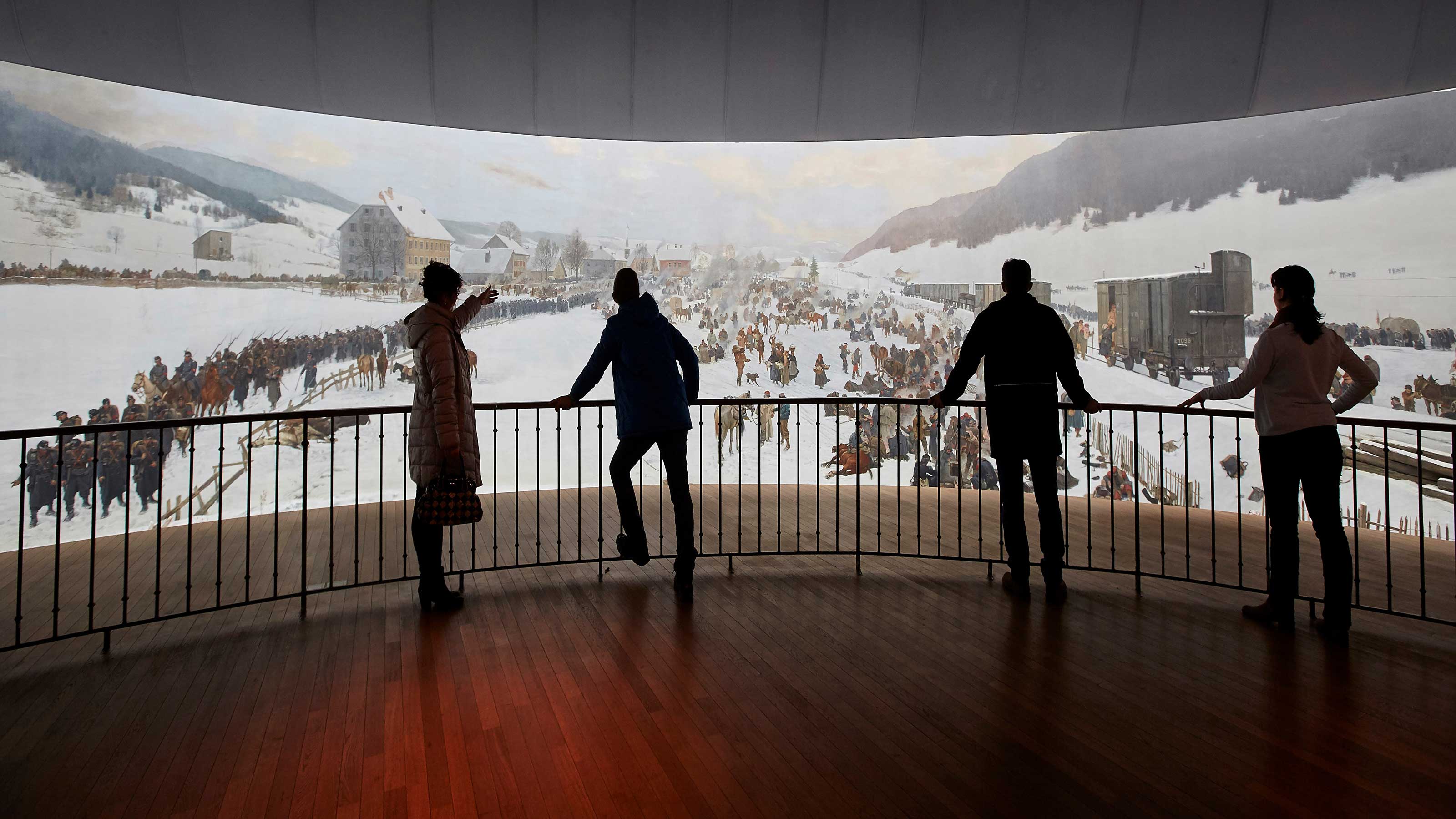 Eine Gruppe Menschen steht vor dem imposanten Rundbild im Bourbaki Panorama. Darauf zu sehen sind Eindrücke der Internierung französischer Soldaten in der Schweiz.