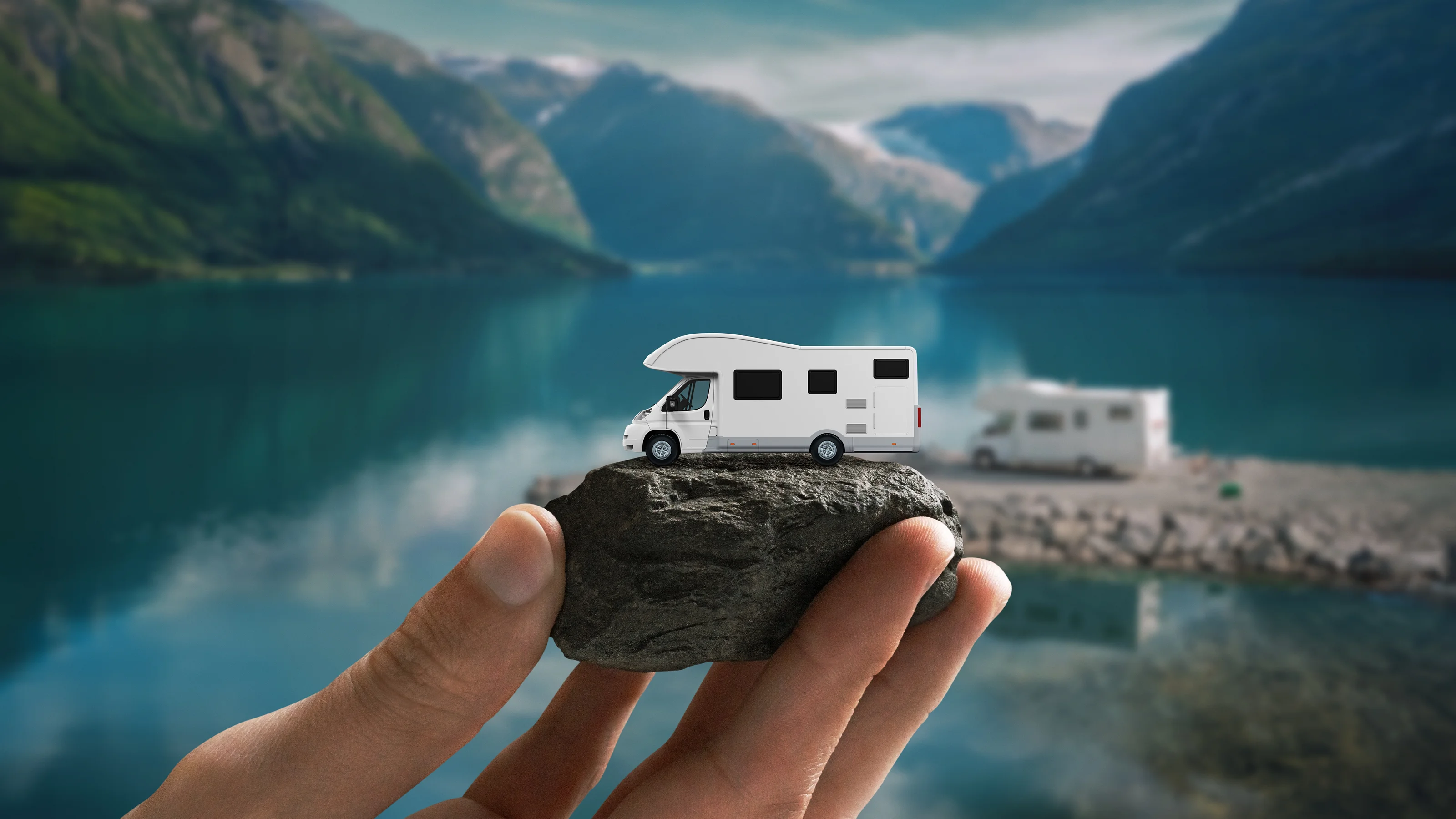 Eine Hand hält einen kleinen Wohnwagen als Symbol für mobiles Reisen am Suisse Caravan Salon.