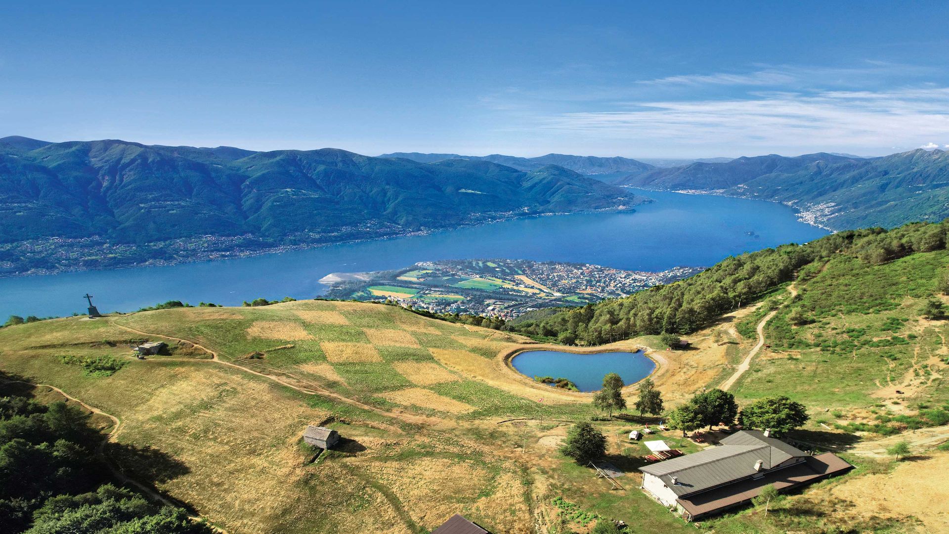 Magnifique photo panoramique avec vue sur le Lac Majeur, entouré de paysages montagneux verdoyants.