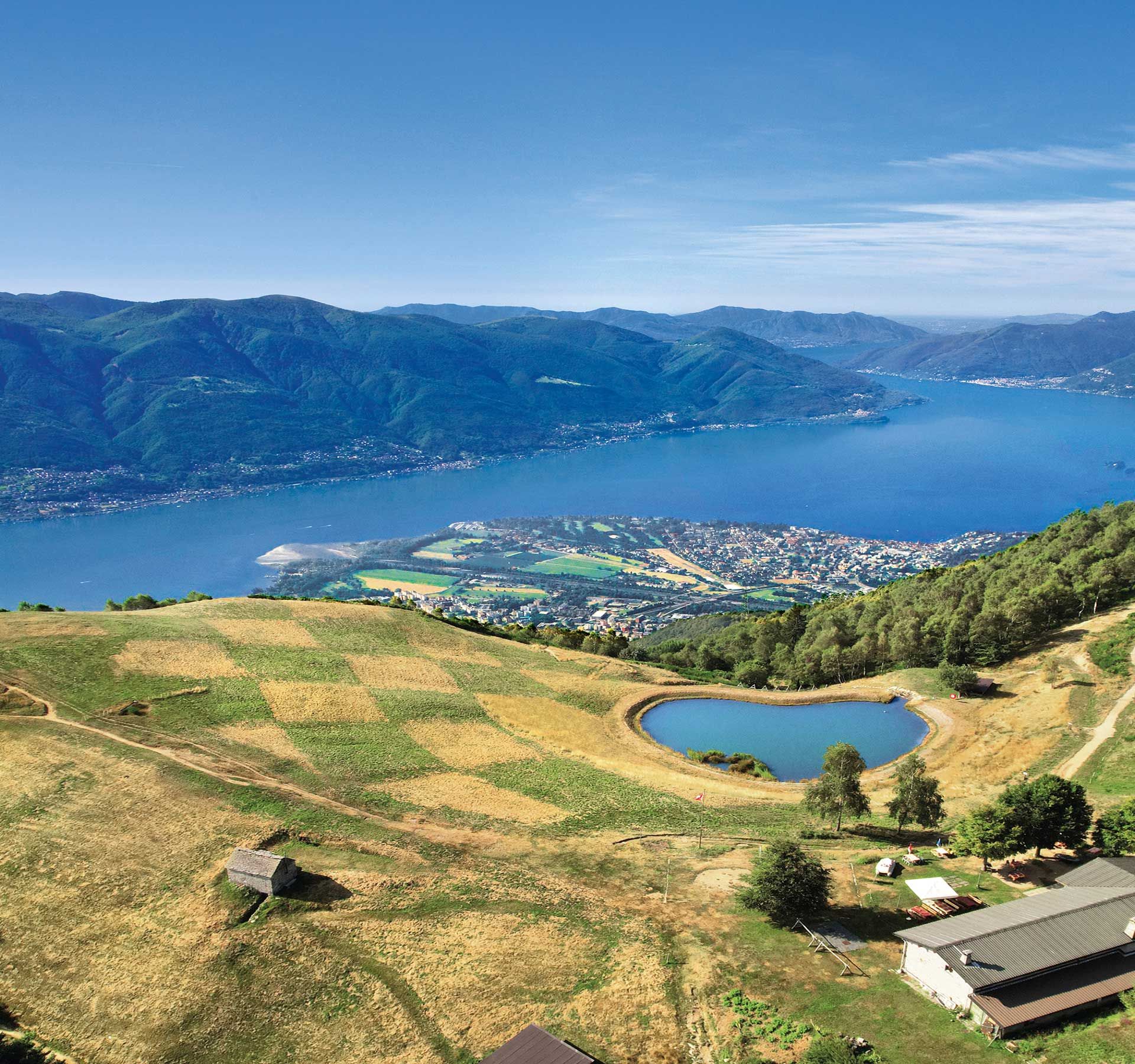 Bellissima foto panoramica con vista sul Lago Maggiore, circondata da verdi paesaggi montani.
