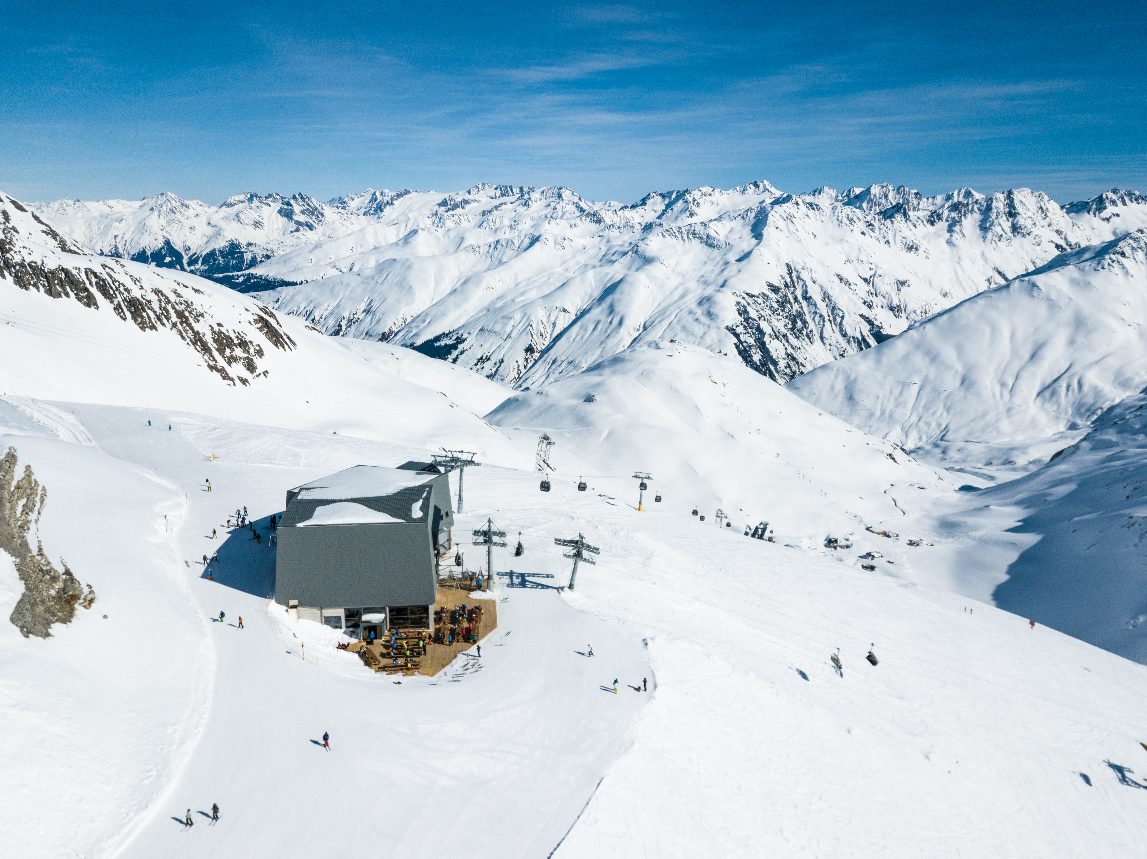 Schneehüenerstock Andermatt – skiers on the slopes with stunning views of the snow-covered Gotthard massif and the Swiss Alps.