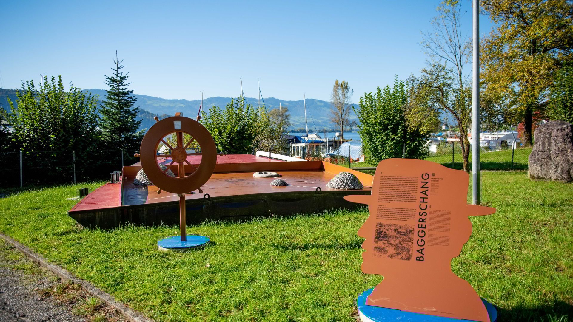 Obersee Discovery Trail with an interactive “Baggerschang” station near Rapperswil, surrounded by greenery and lake views.