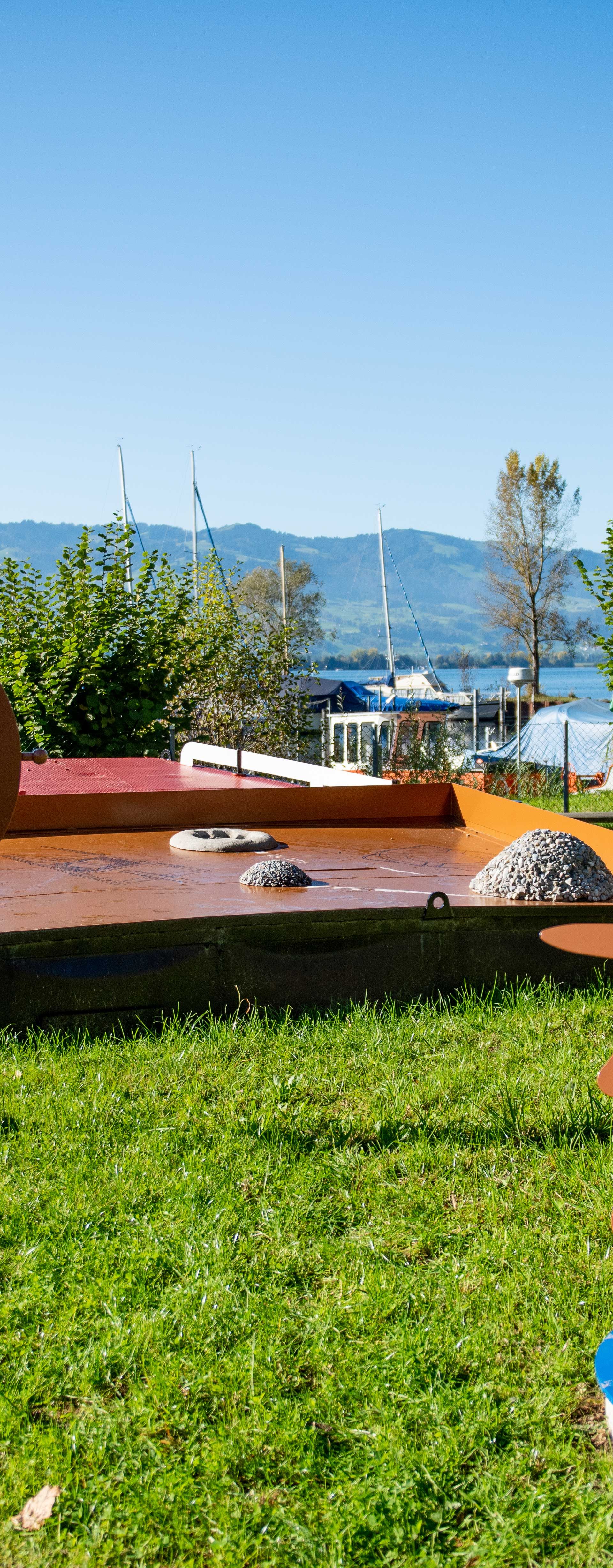 Sentier découverte de l’Obersee avec station interactive « Baggerschang » près de Rapperswil, entouré de verdure et du lac.