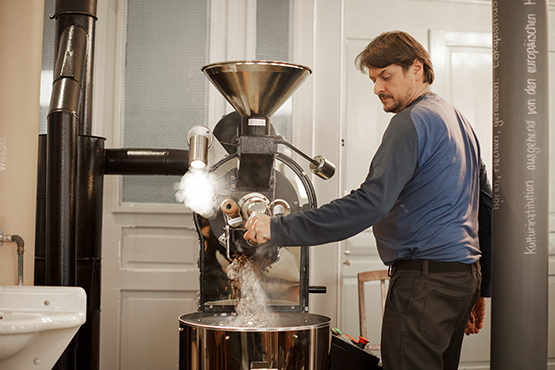 Dampfende Kaffeeröstmaschine im Kaffeehaus Linsebühl – frische Bohnen fallen in den Auffangbehälter.