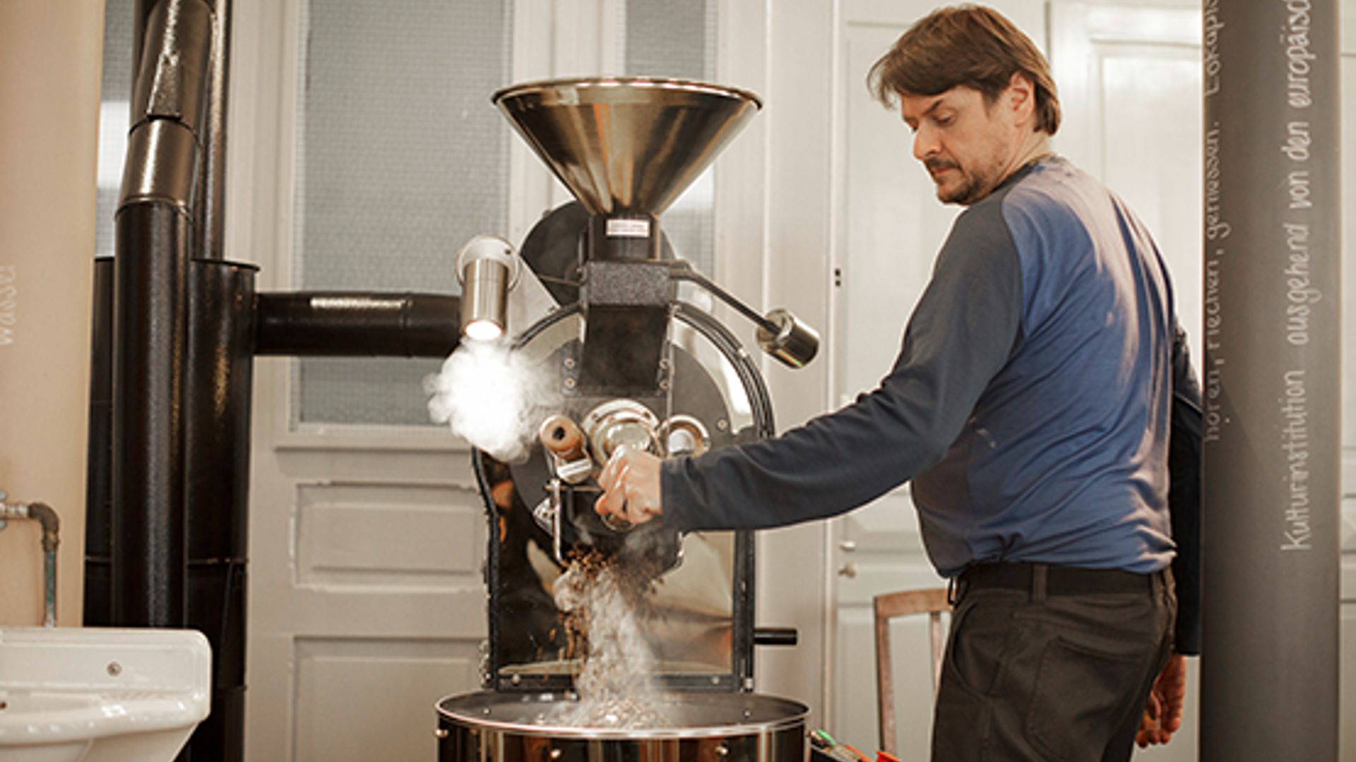 Steaming coffee roaster at the Linsebühl coffee house – fresh beans fall into the collection container.