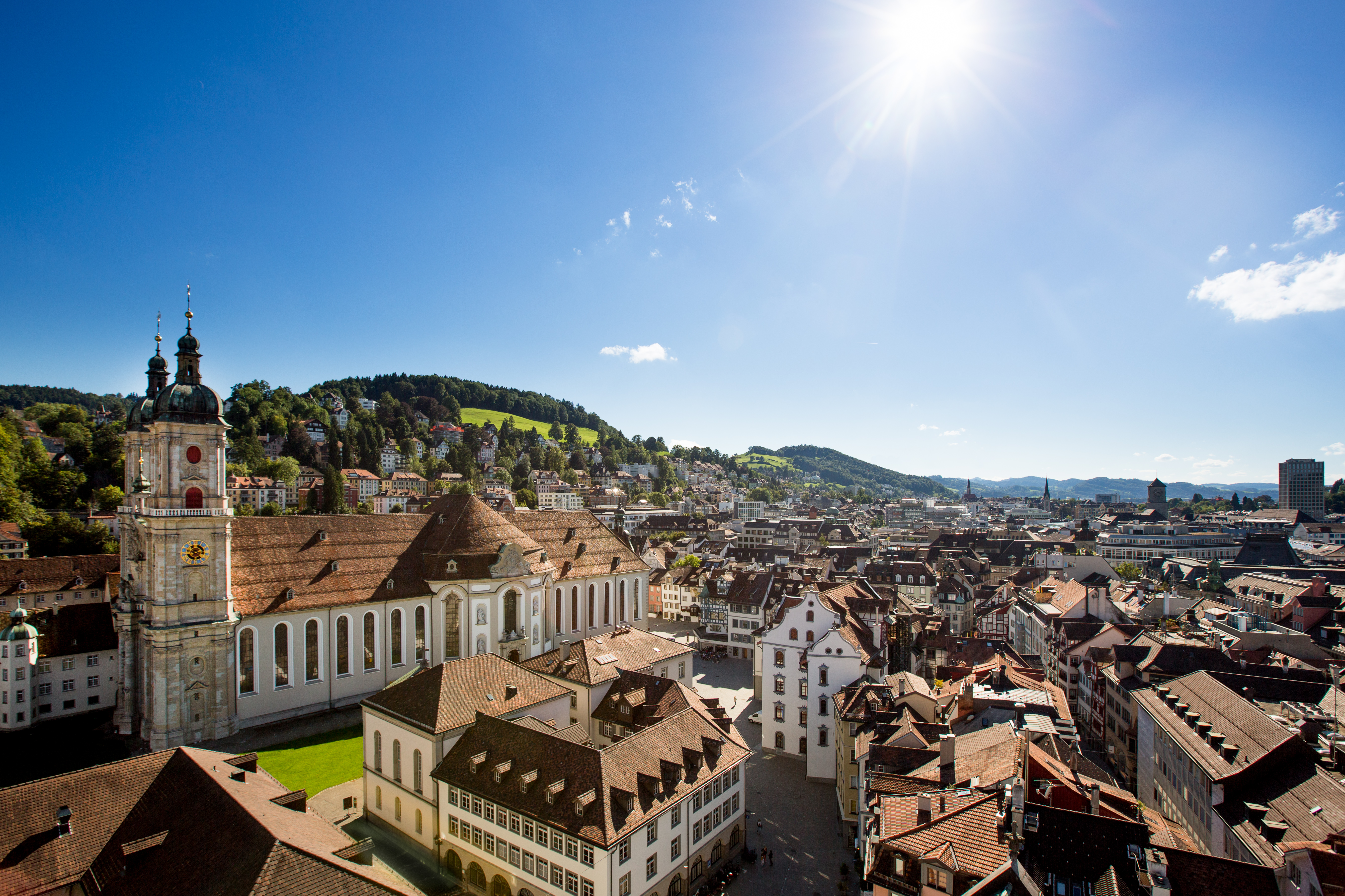 Aerial view of the Abbey District of St. Gallen with the baroque cathedral and the historic old town in bright sunlight.