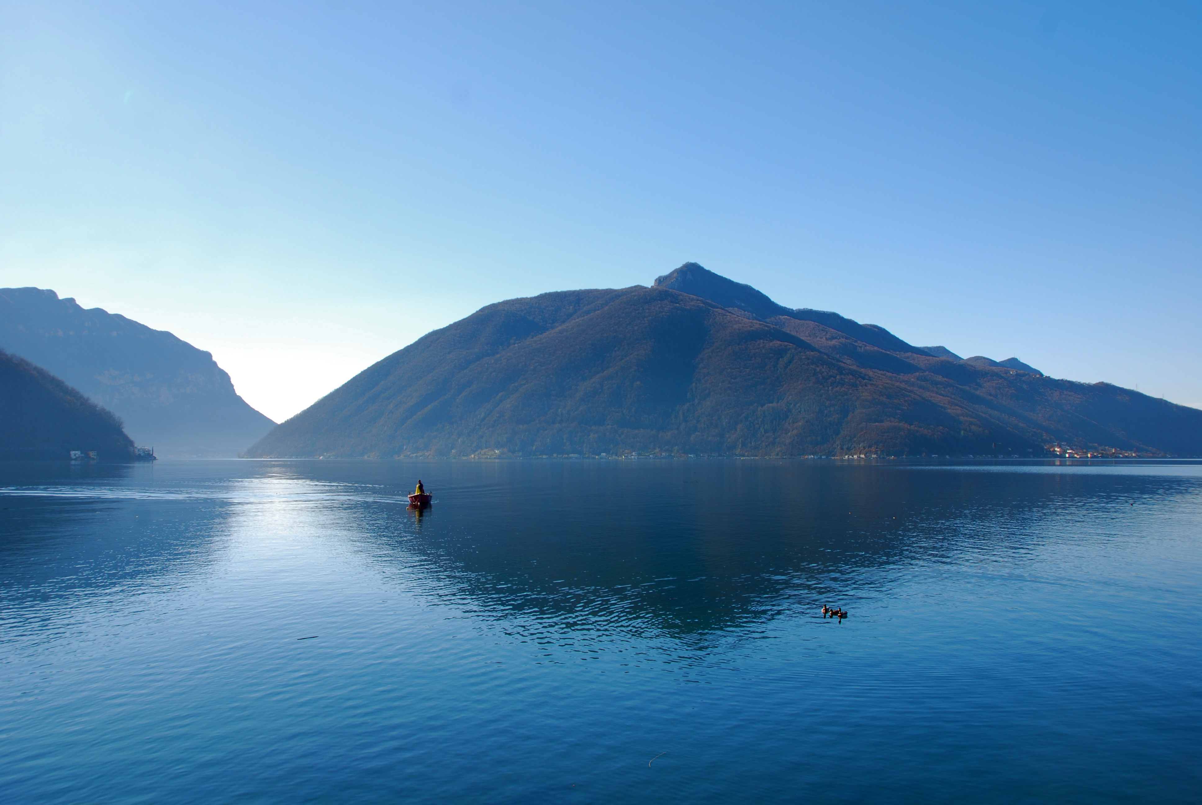 blauer See mit Berg und Bäumen im Hintergrund