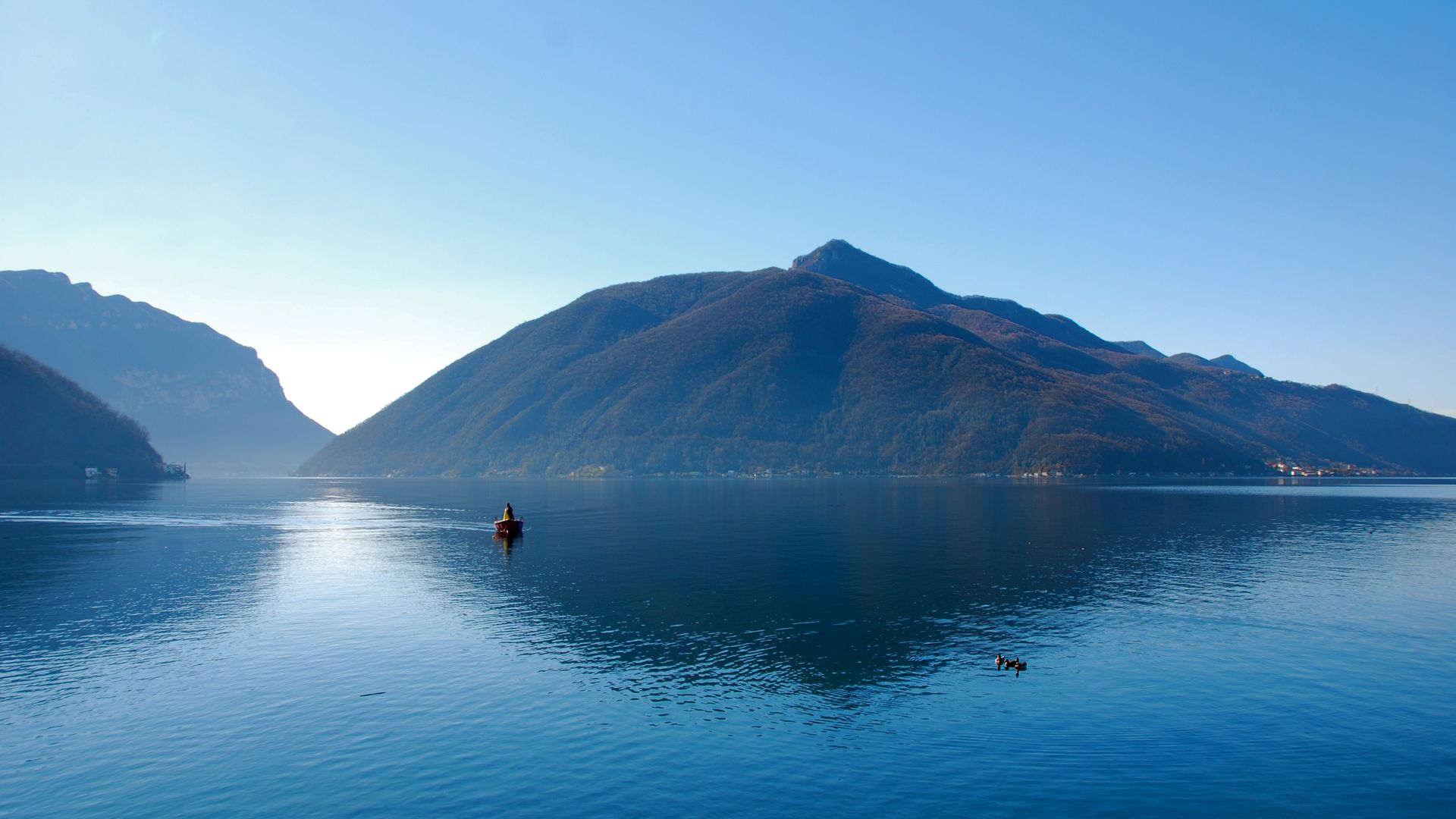 blauer See mit Berg und Bäumen im Hintergrund